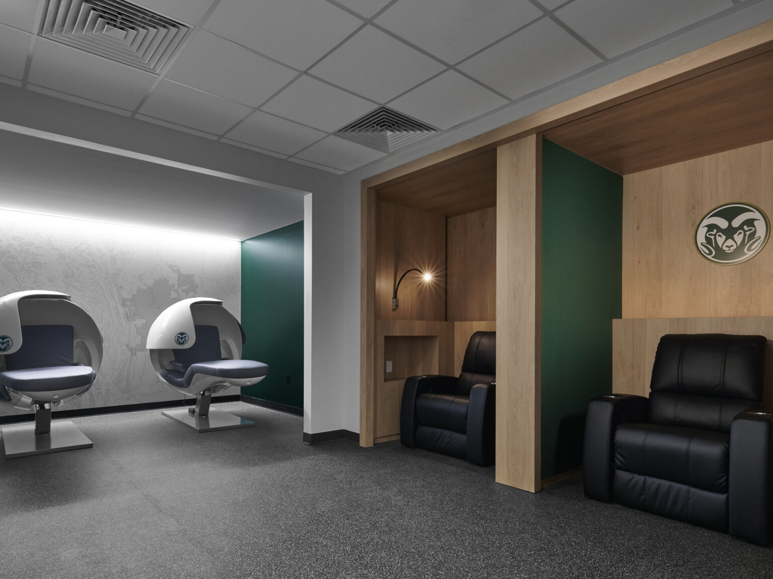 rehab room for athletes, two massage chairs and various other rehab seating, signage on white oak paneled wall