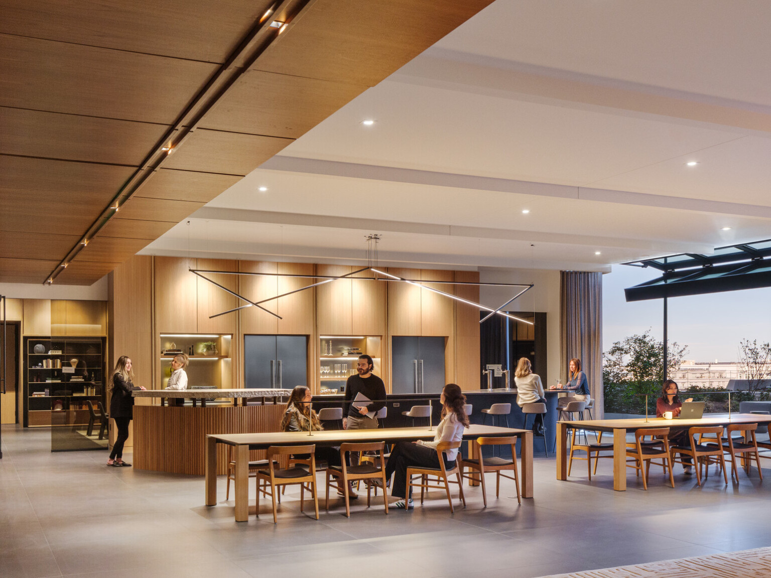 A modern office space with wooden decor, people interacting at tables, and large windows offering outdoor views. A modern office space with wooden decor, people interacting at tables, and large windows offering outdoor views.