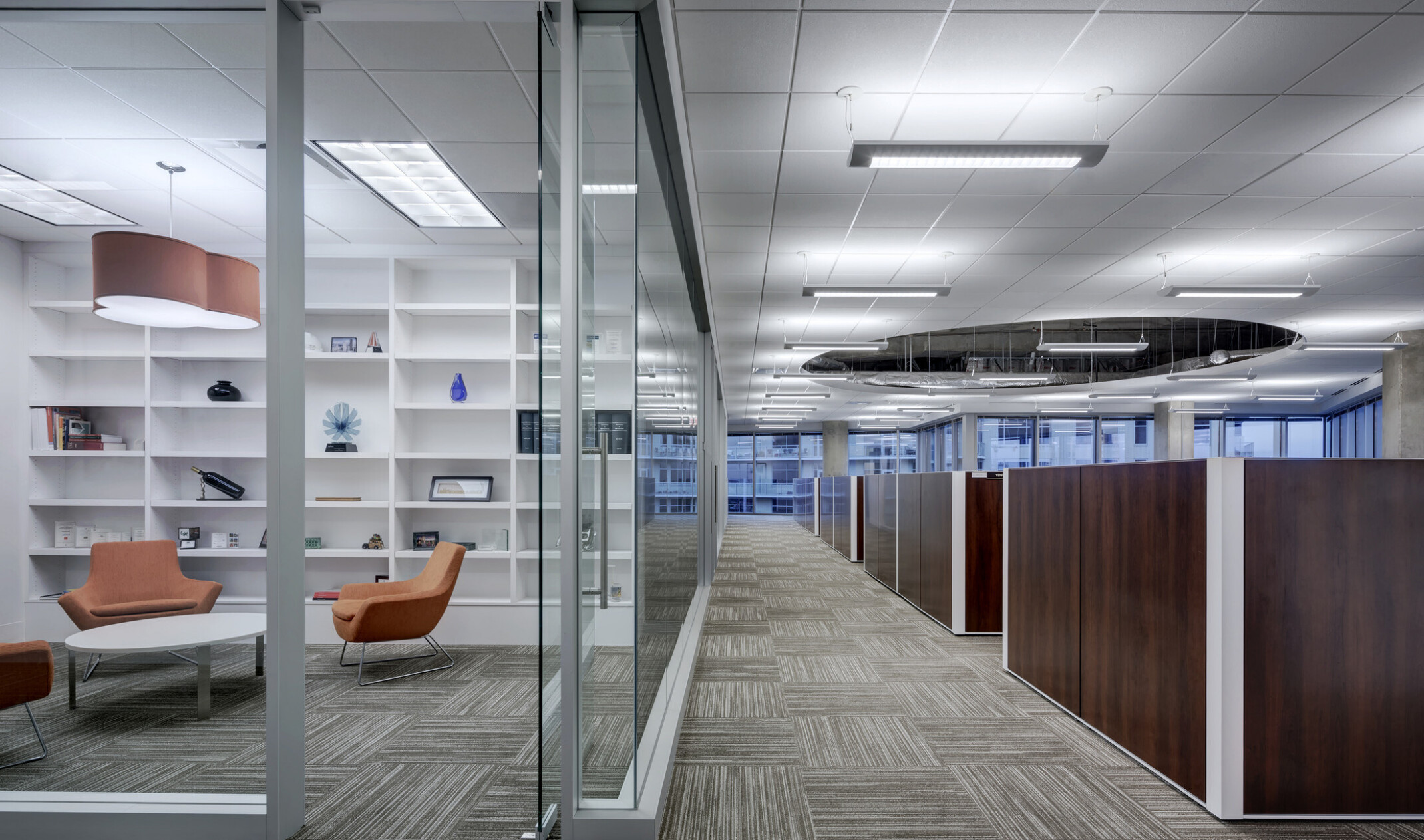 modern office walkway; modular furniture in the forefront with a glass fishbowl conference room in the background