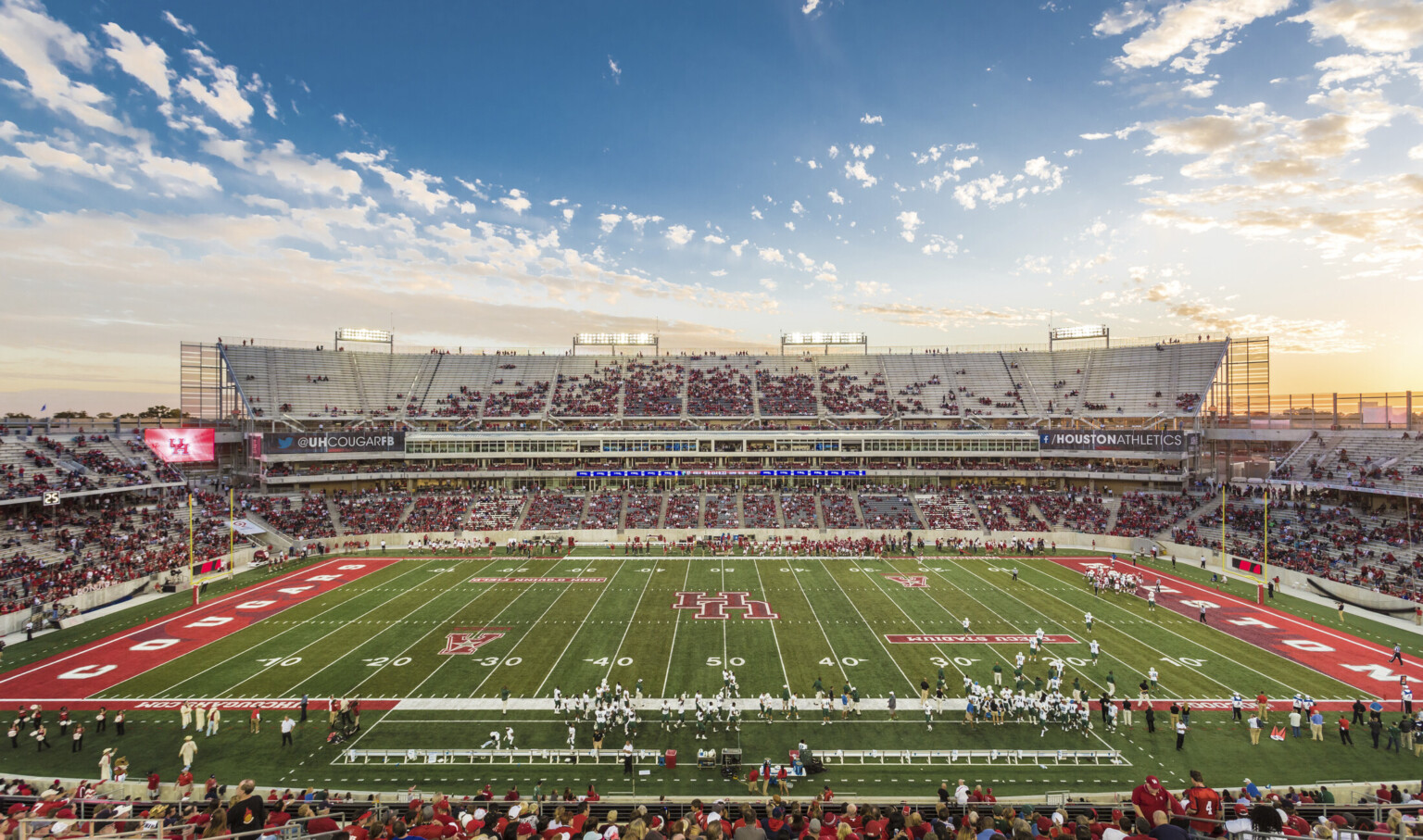 View of football field from upper deck seating at 50 yard line. Red end zones with Houston Cougars written across them View of football field from upper deck seating at 50 yard line. Red end zones with Houston Cougars written across them