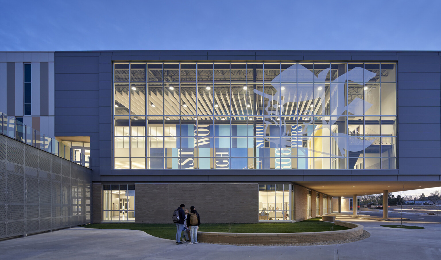 Exterior view looking in to double height windows with translucent image of the Troop mascot. Inside is blue colorblock mural