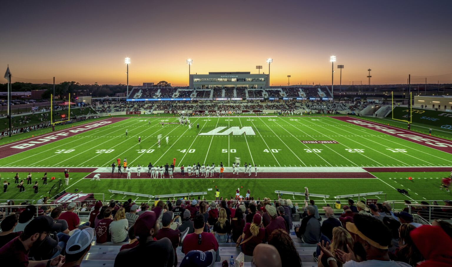 Rendering of football field seen from upper deck seating at 50 yard line. Dark red end zones with Buffaloes written on each