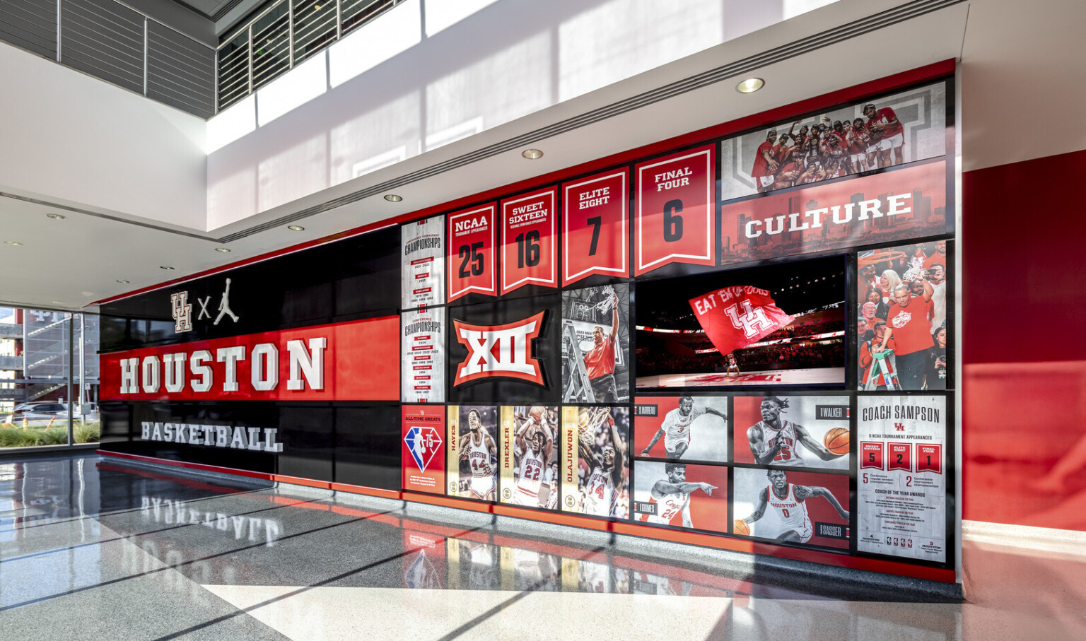 interior of a sports facility; Large black and red "HOUSTON" wall with sports collage of athletes. coaches, awards. stats