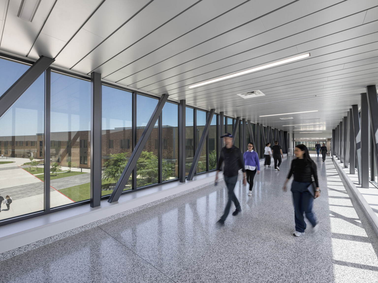 Large skywalk surrounded by windows on each side. Large black floor to ceiling beams, grey floors and ceiling Large skywalk surrounded by windows on each side. Large black floor to ceiling beams, grey floors and ceiling
