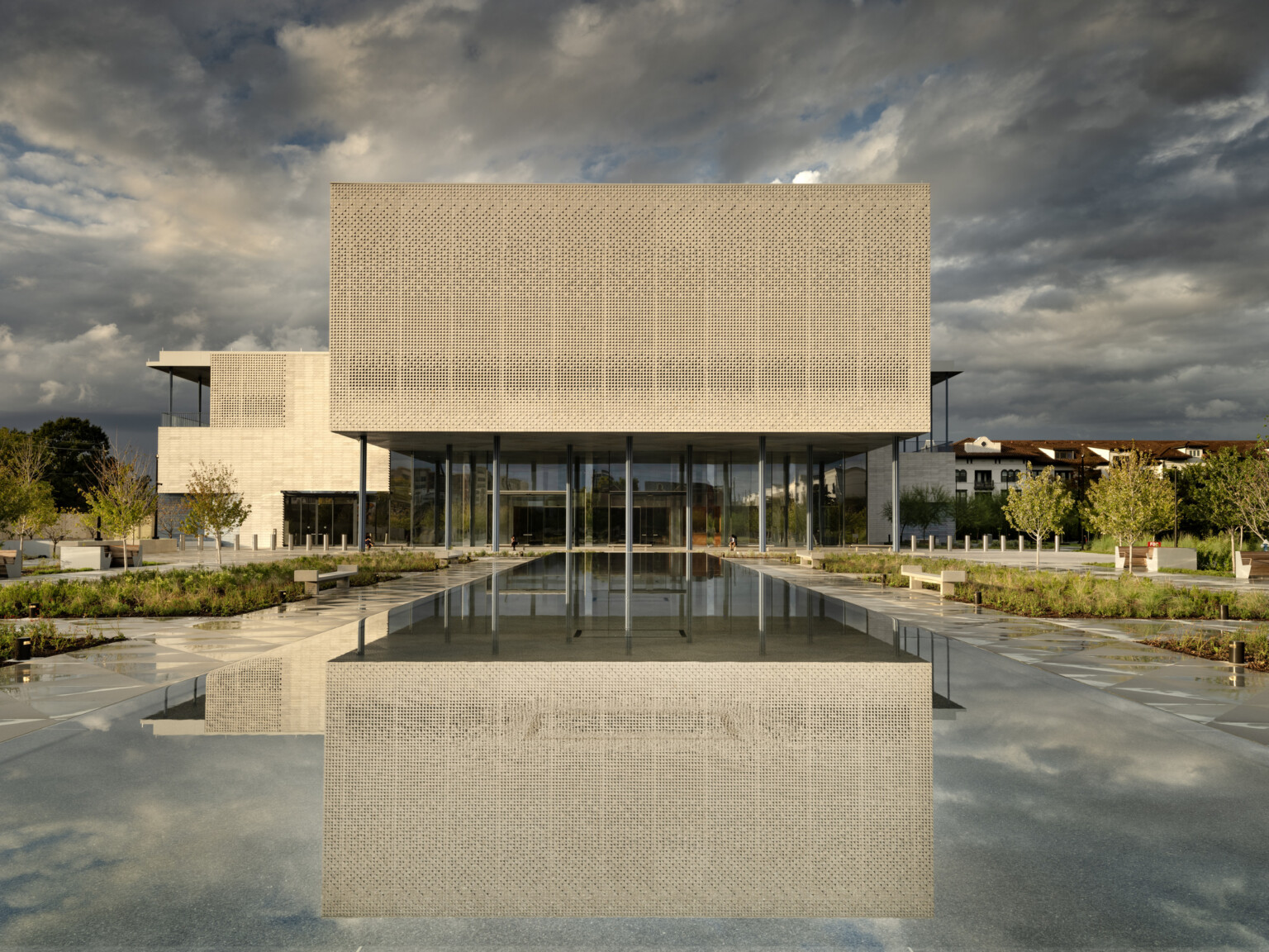 Intricately patterned screens on the building exterior of a building against a reflection pool