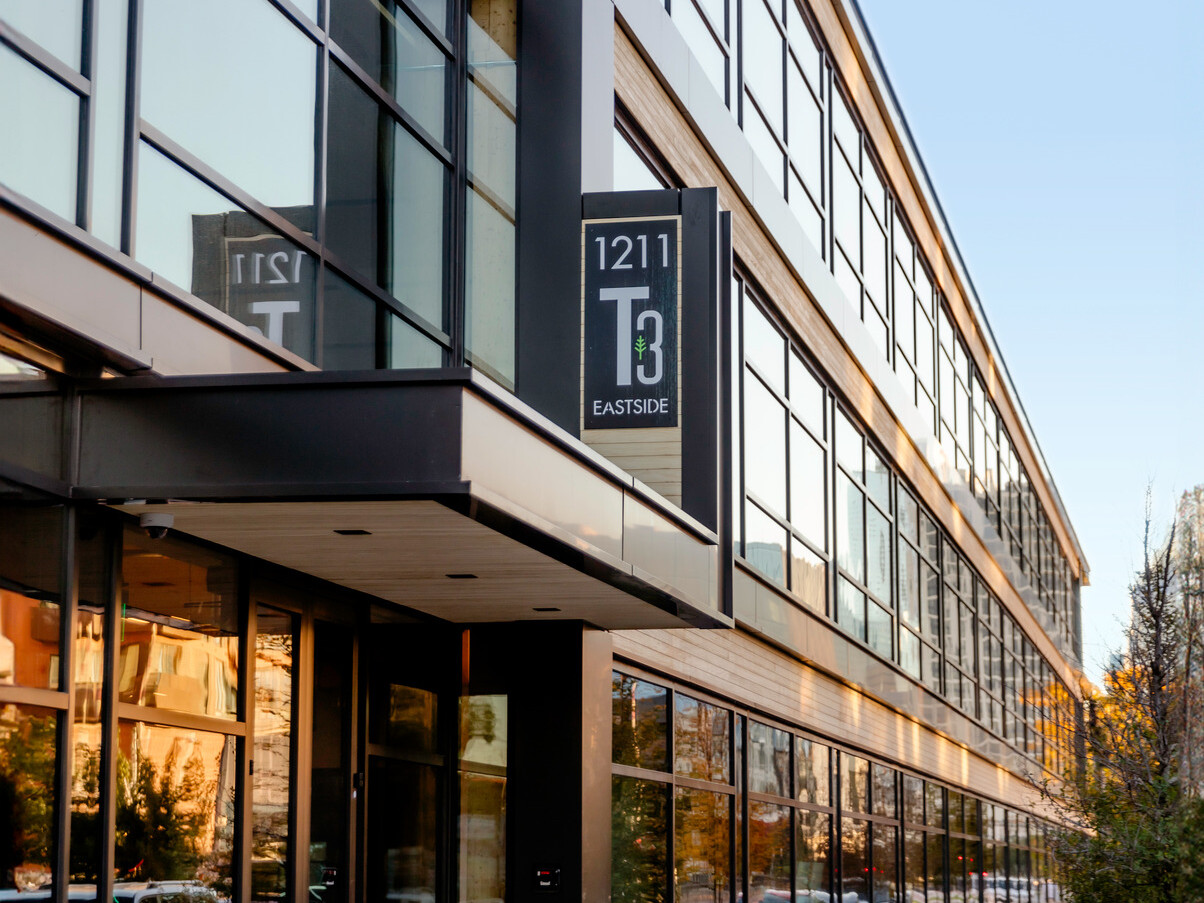 Side view of building with black exposed steel, exposed mass timber and large windows with a T3 sign Side view of building with black exposed steel, exposed mass timber and large windows with a T3 sign