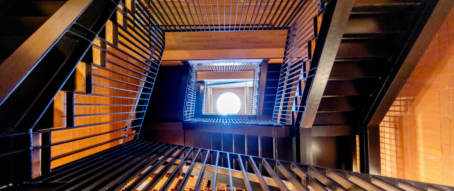 Bottom of a multistory staircase looking up at a window through the railings