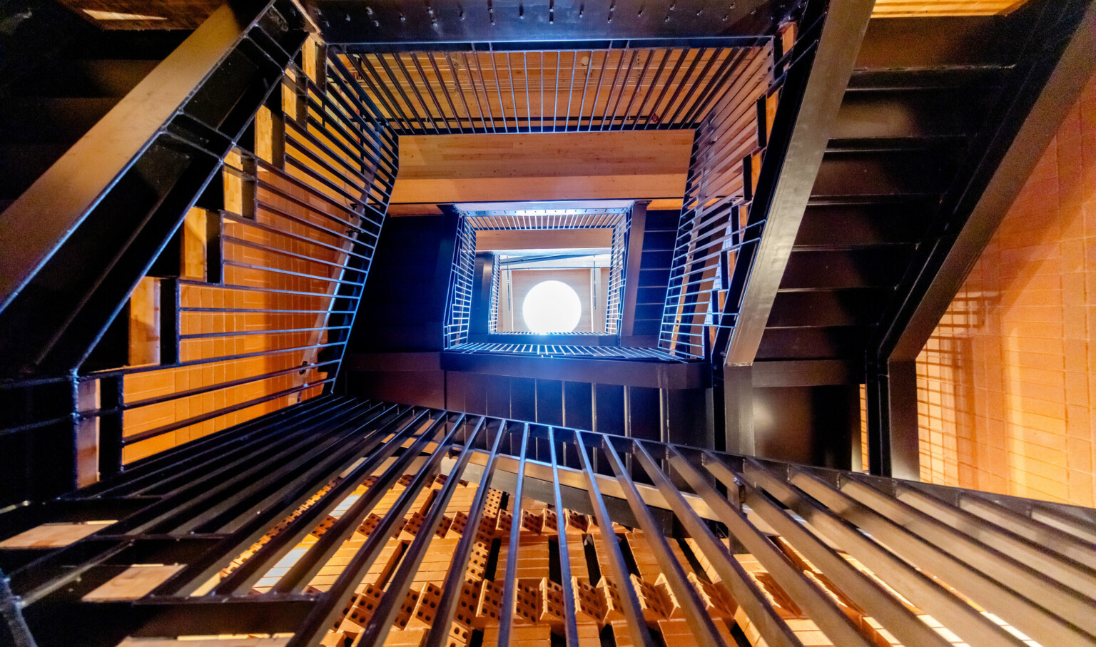 Bottom of a multistory staircase looking up at a window through the railings