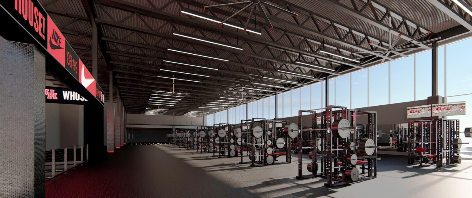 Natural light floods the fitness training center weight room, clerestory windows, high-ceilings, branding signage, state-of-the-art training equipment
