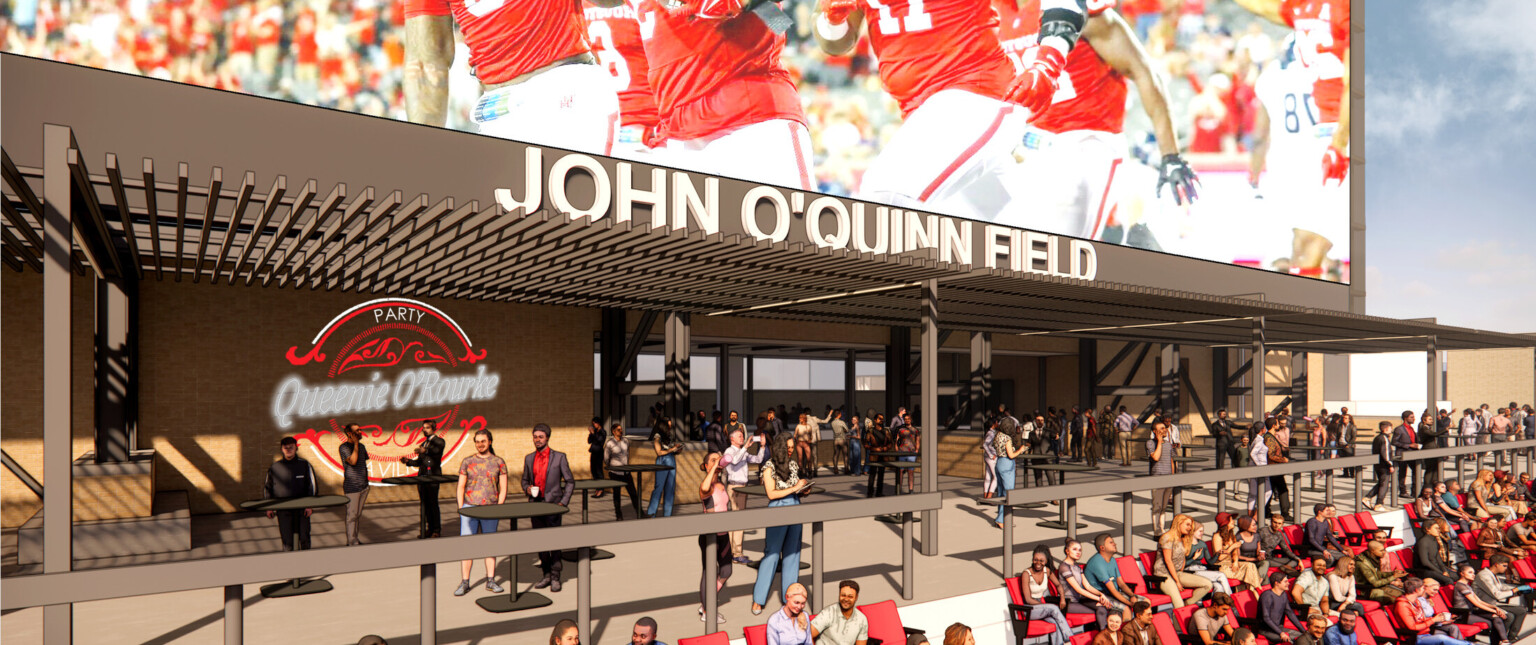 Outdoor patio with large screen, red seating filled with people with branding on the back walls