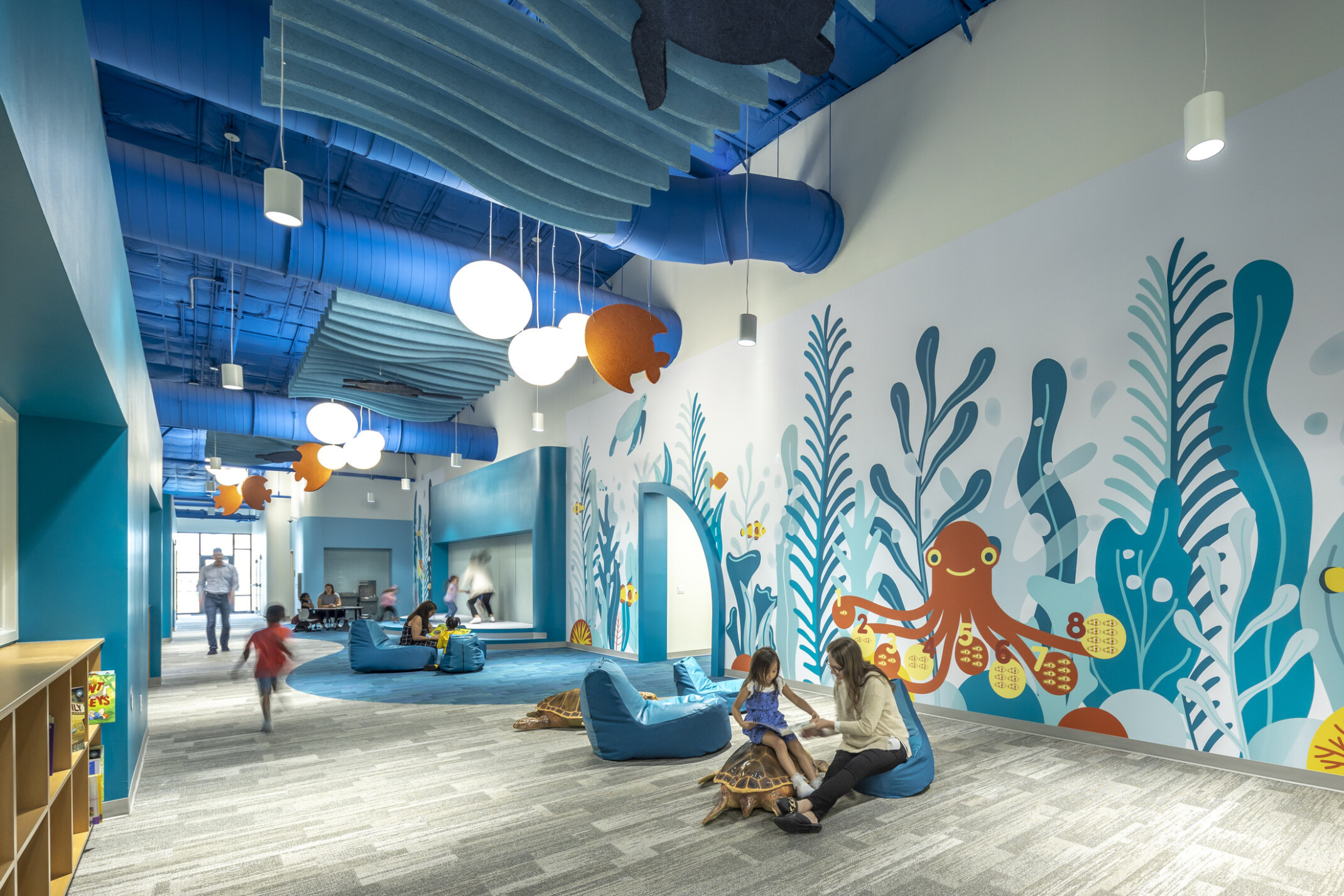 excellence early learning center with colorful ocean murals in blues and orange on the back wall. Light wood flooring and modern furniture.