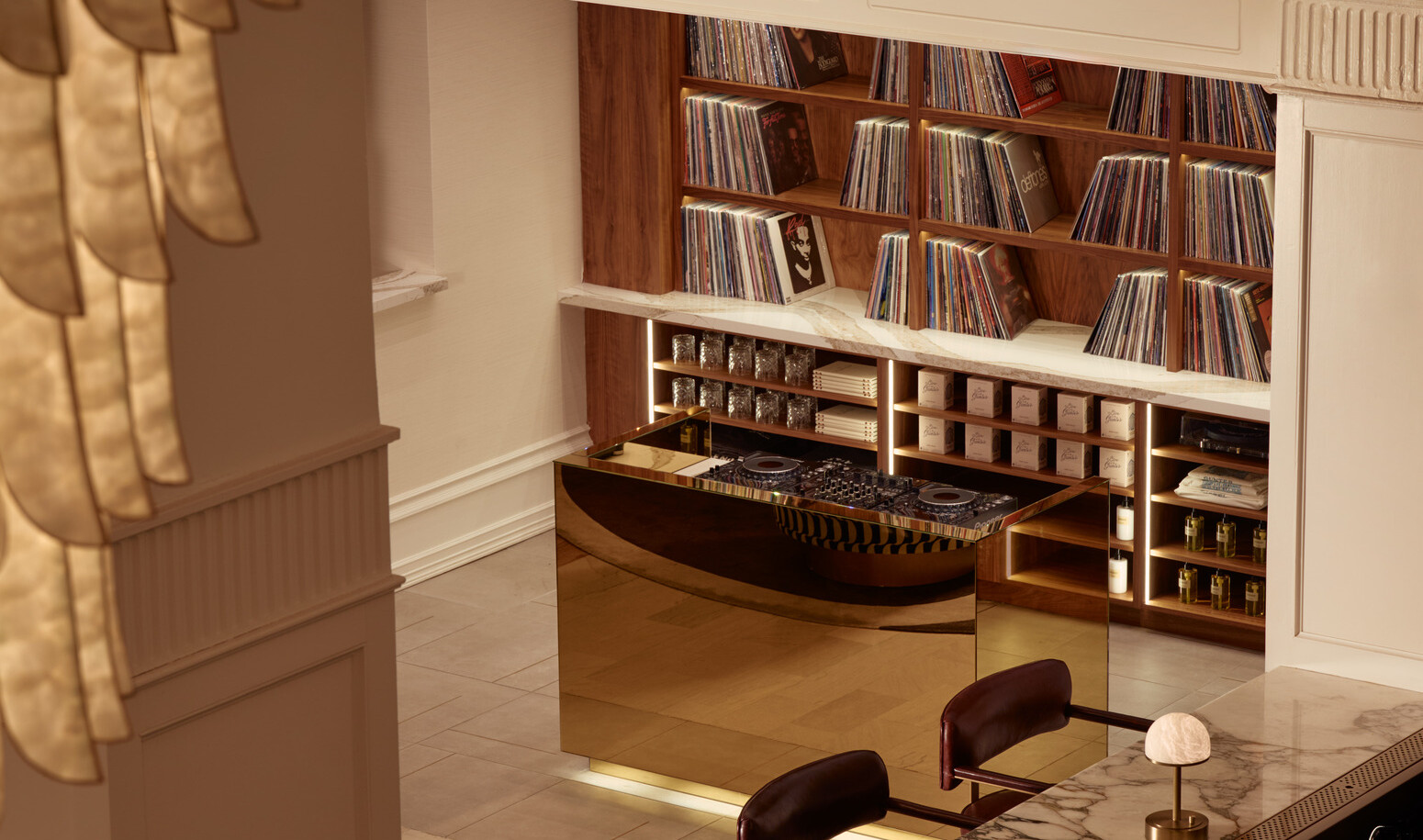 Elevated view of the Gunter Hotel’s gold DJ booth and record library, with a glimpse of the Keystone Club bar and a chandelier above.