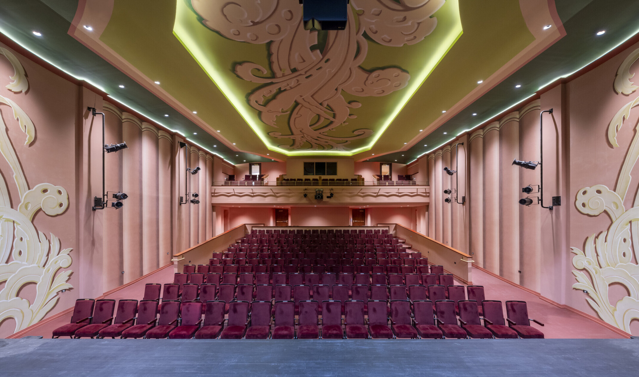 interior of an art deco theater hall; stage view of the audience with pink walls and ceilings with floral designs