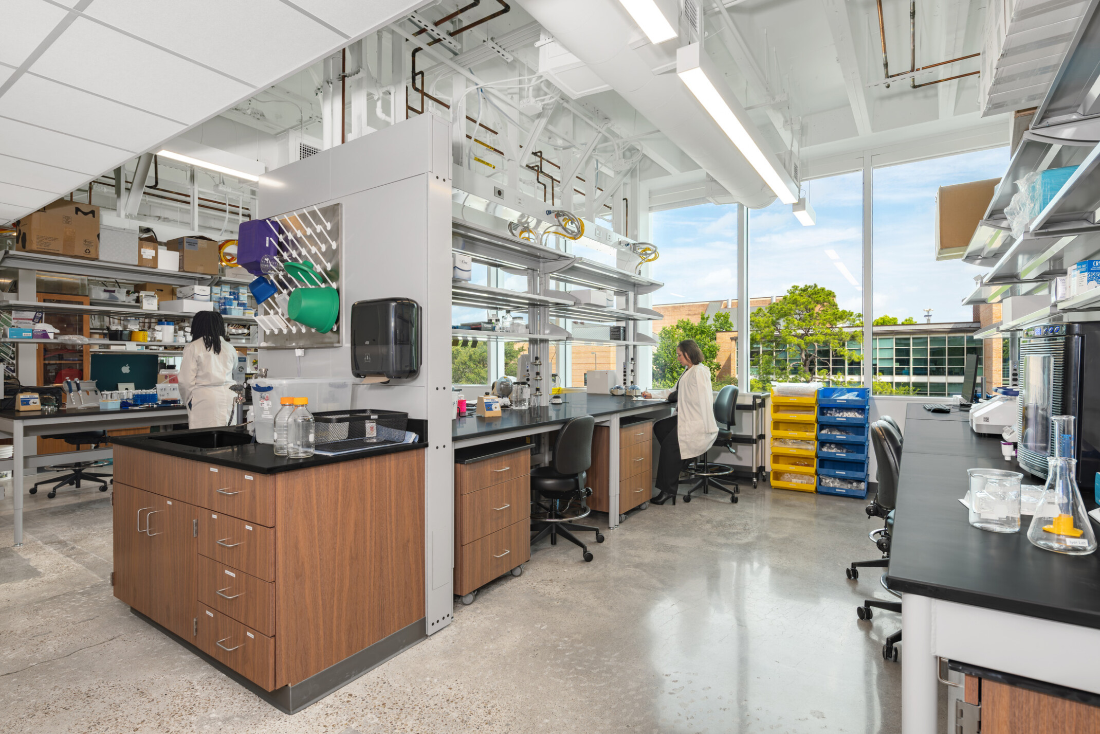Bright, modern lab with two people working at separate stations among equipment and supplies.