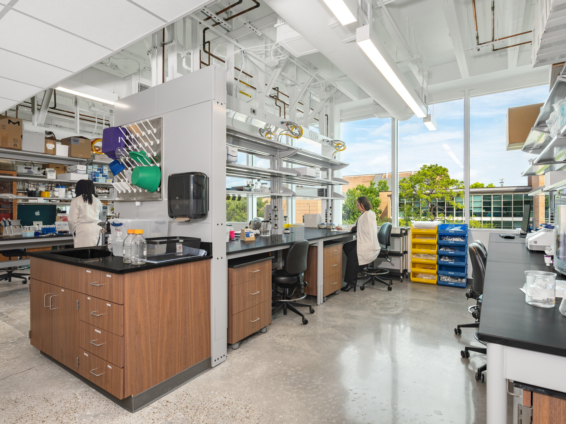 Bright, modern lab with two people working at separate stations among equipment and supplies.