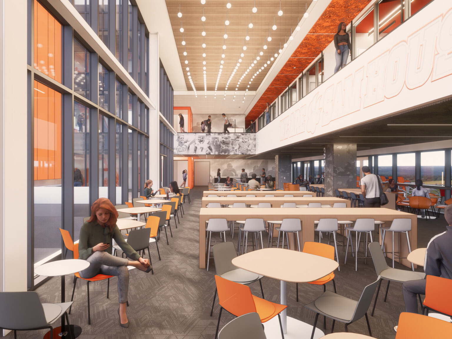 Interior of a modern sports stadium with large floor to ceiling windows, orange and gray seating, and an upper balcony overlooking the first floor