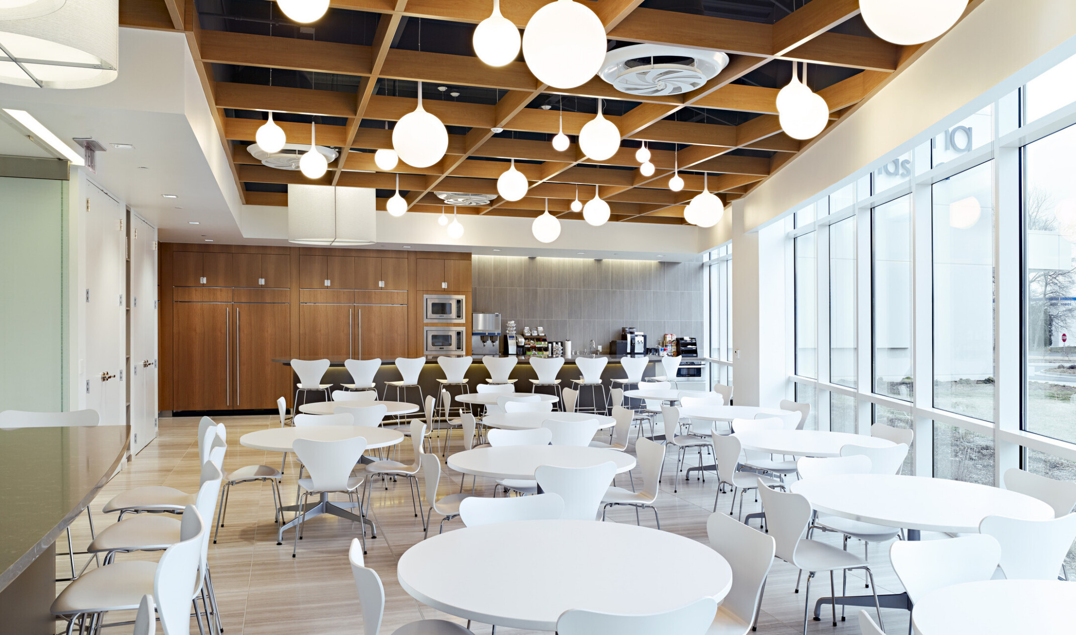 dining area with white circle tables, warm wood walls, and lit up globe pendants hanging from the ceiling