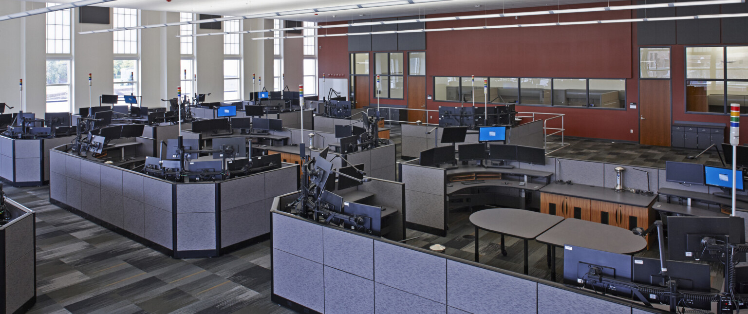 Interior call center office space with cubicles filled with desks with multiple monitors