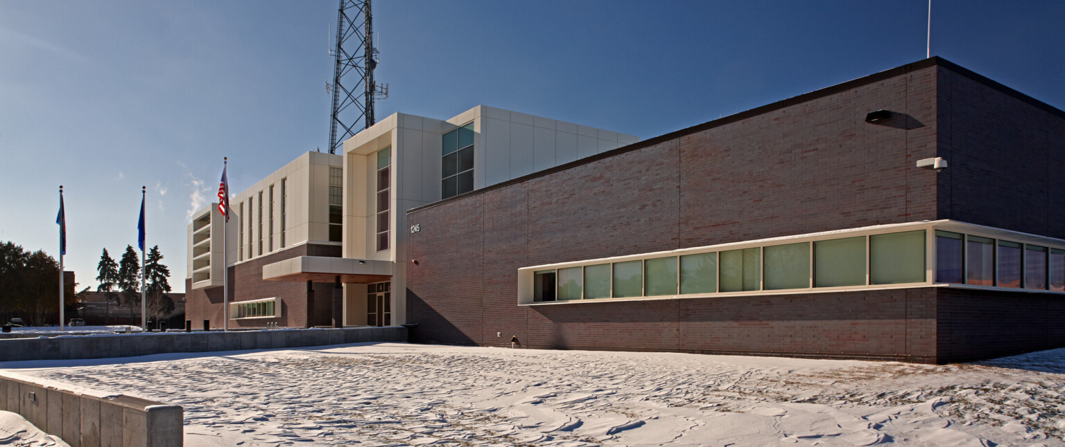 Multistory building with a dark brown bottom and white top with three flags flying out front
