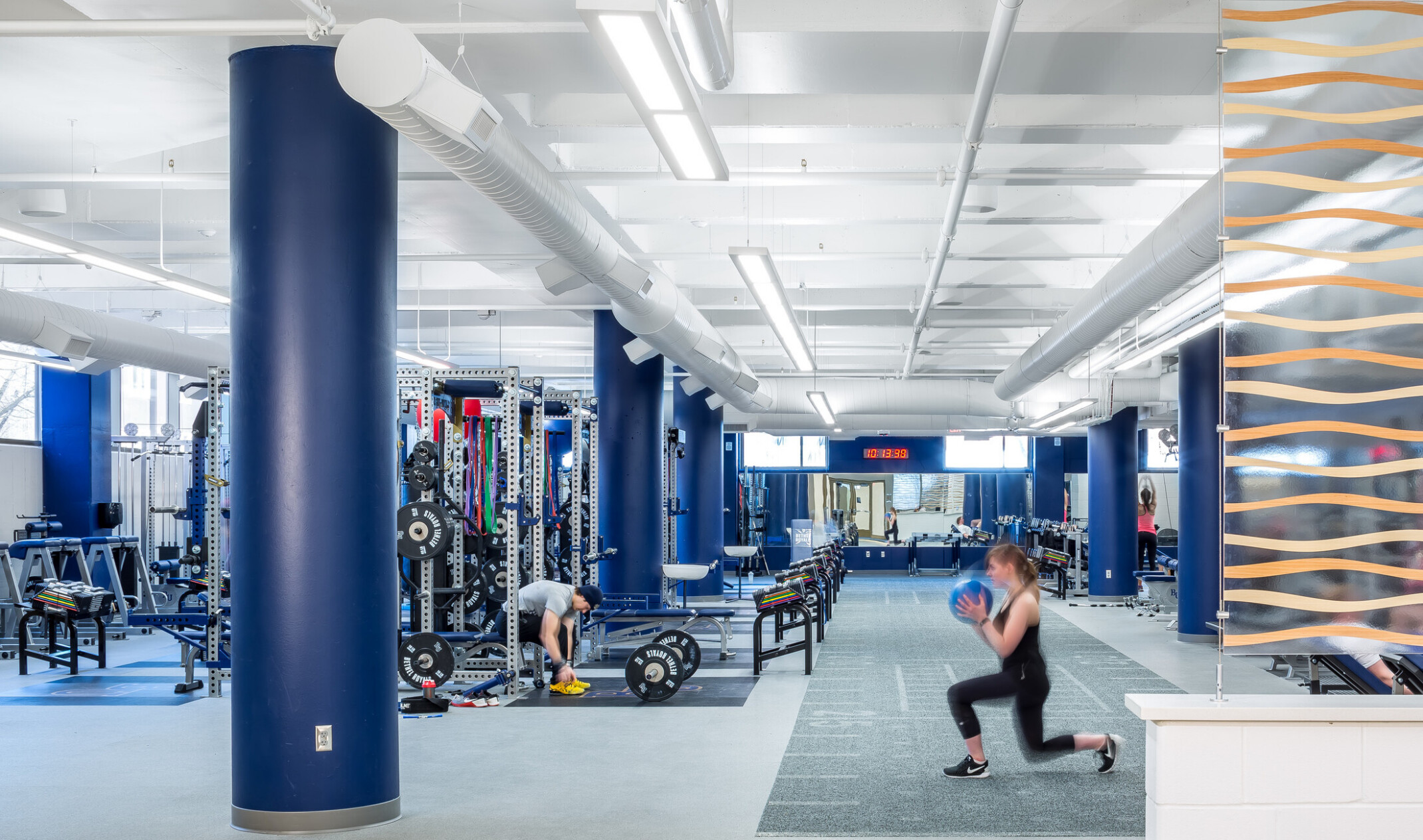 modern gym space with people working out and machines in the background