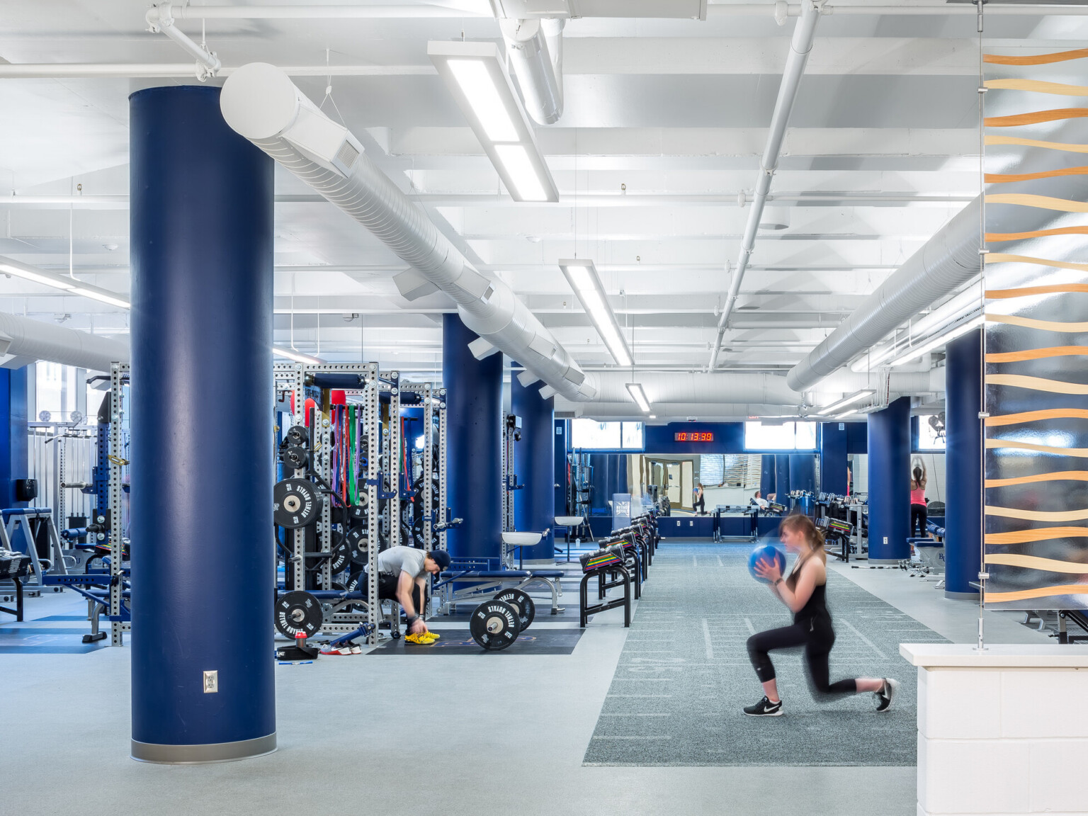 modern gym space with people working out and machines in the background