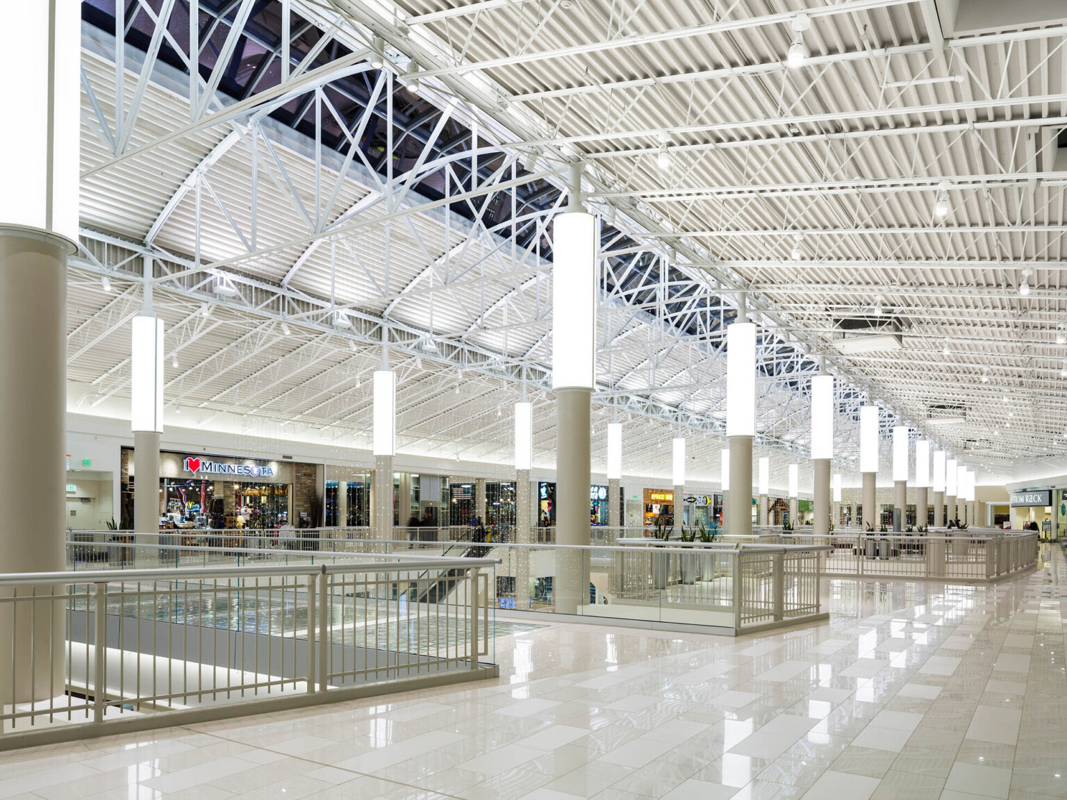 three level atrium with white finishes and truss supports along a skylight