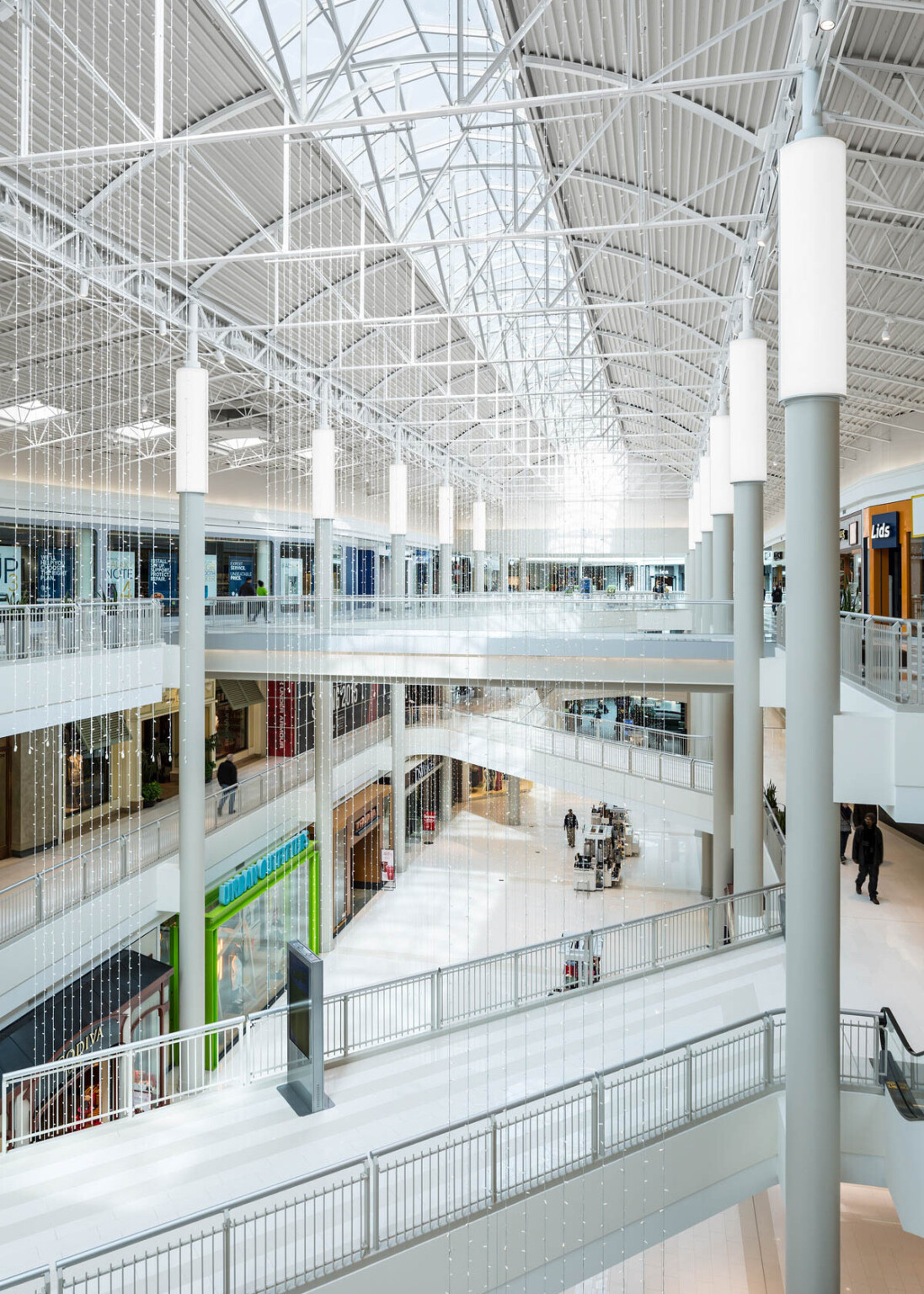 three level atrium with white finishes and truss supports along a skylight