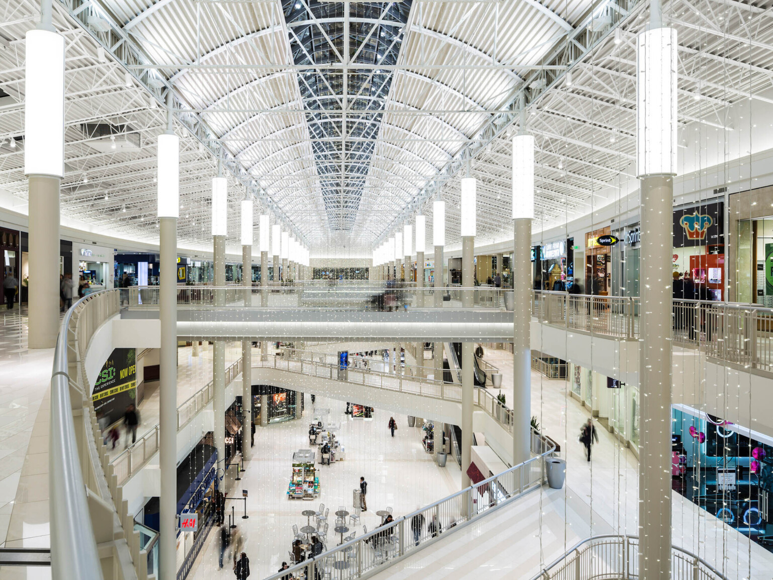 three level atrium with white finishes and truss supports along a skylight