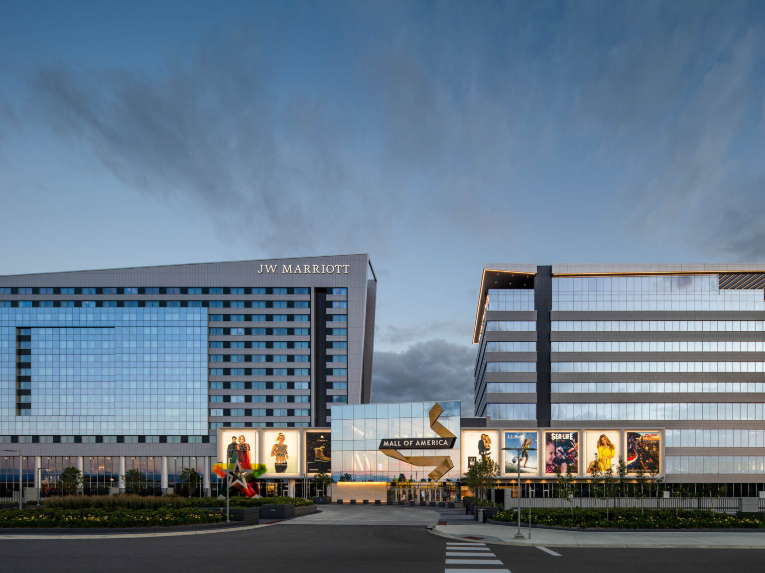 Mall of America entry with illuminated signage connects 2 grey angled buildings. Left building has JW Marriott written at top