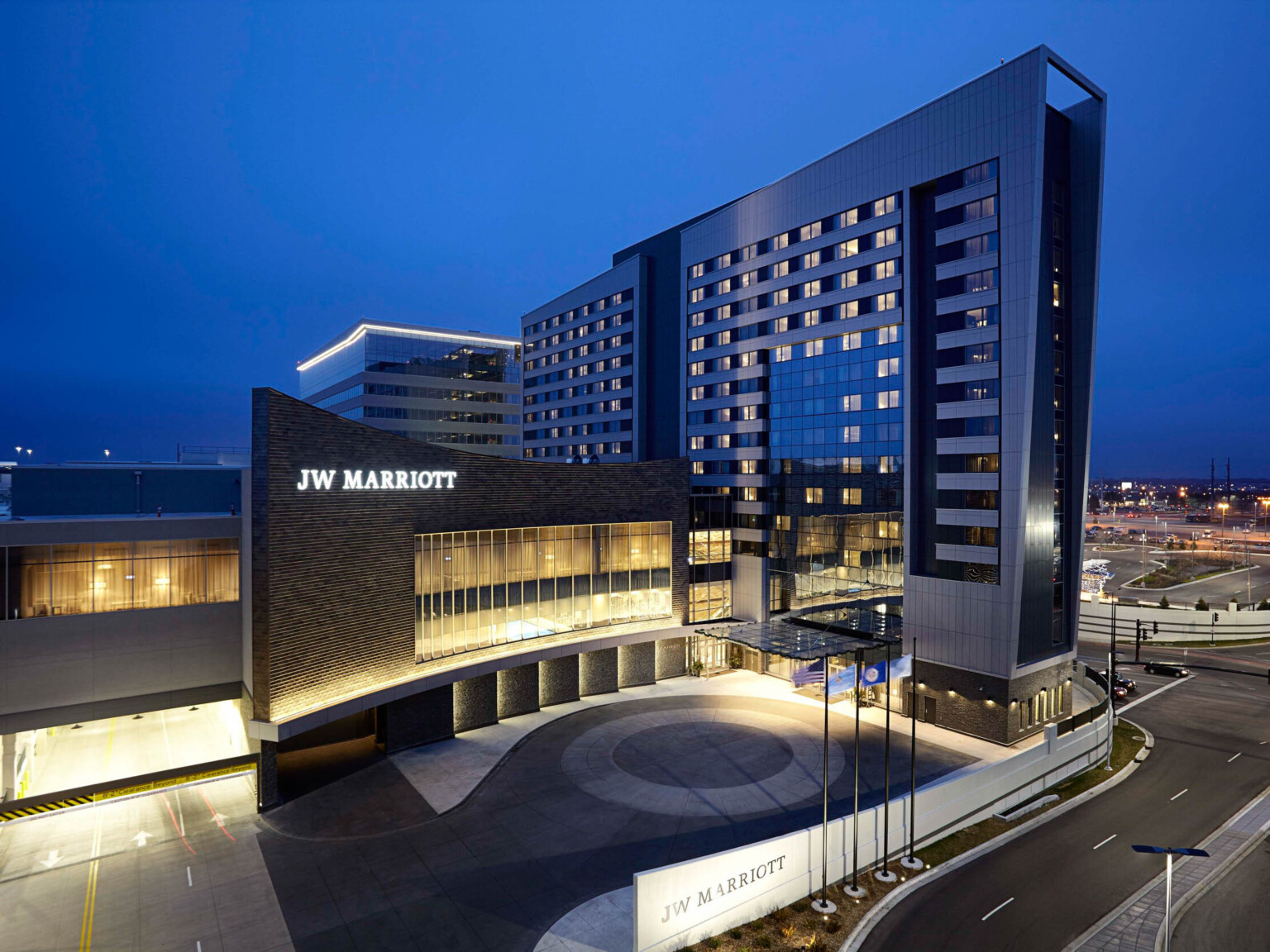 The JW Marriott Hotel and Mall of America illuminated at night. Sign lit on wall with large windows behind round driveway