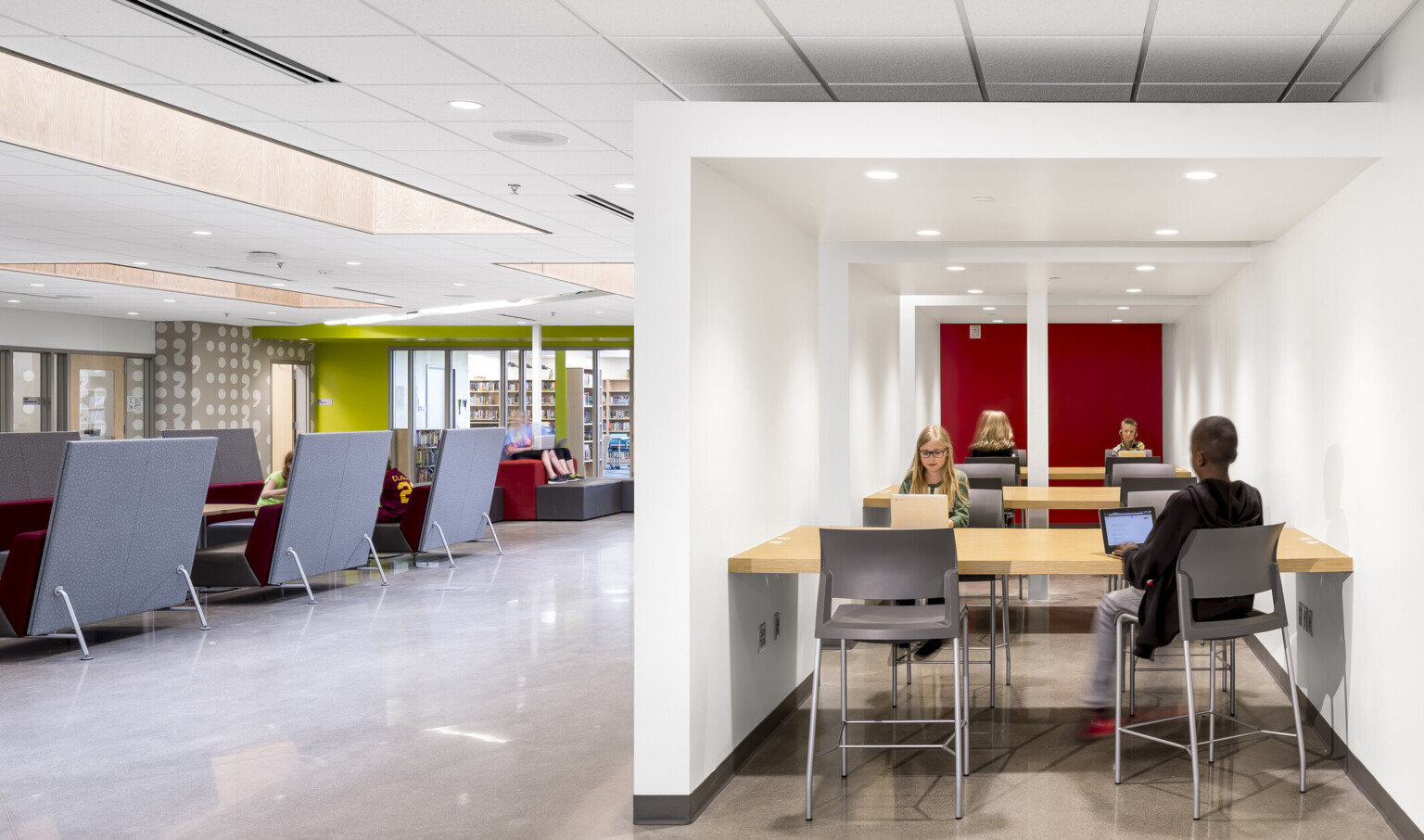 2 images. Left, couches with recessed ceiling panels of light. Right, a sectioned alcove with wood tables for study space