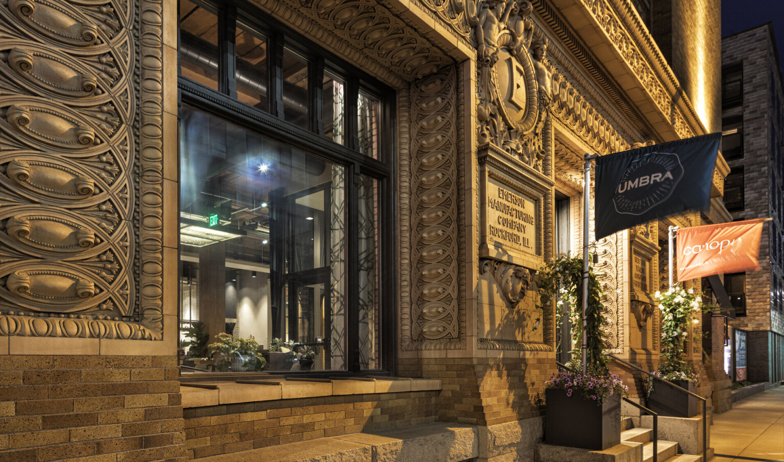 Ornate carved stone molding around entry with historic carved sign reading Emerson Manufacturing Company Rockford, Ill.