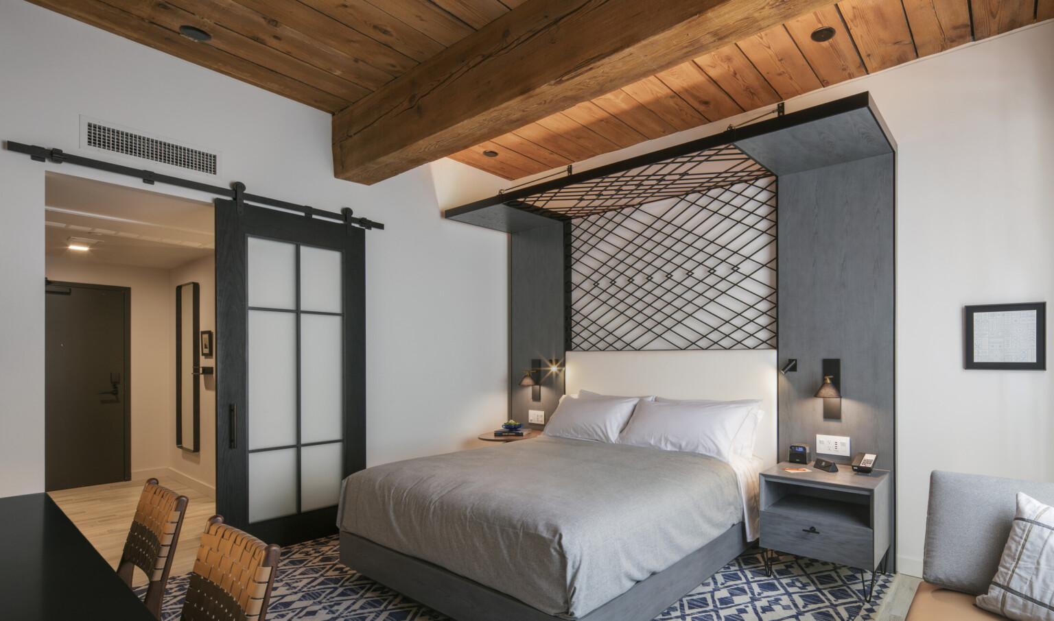 Bedroom with geometric black metal design behind wall and folding over top of bed to form canopy. Left, glass sliding door Bedroom with geometric black metal design behind wall and folding over top of bed to form canopy. Left, glass sliding door