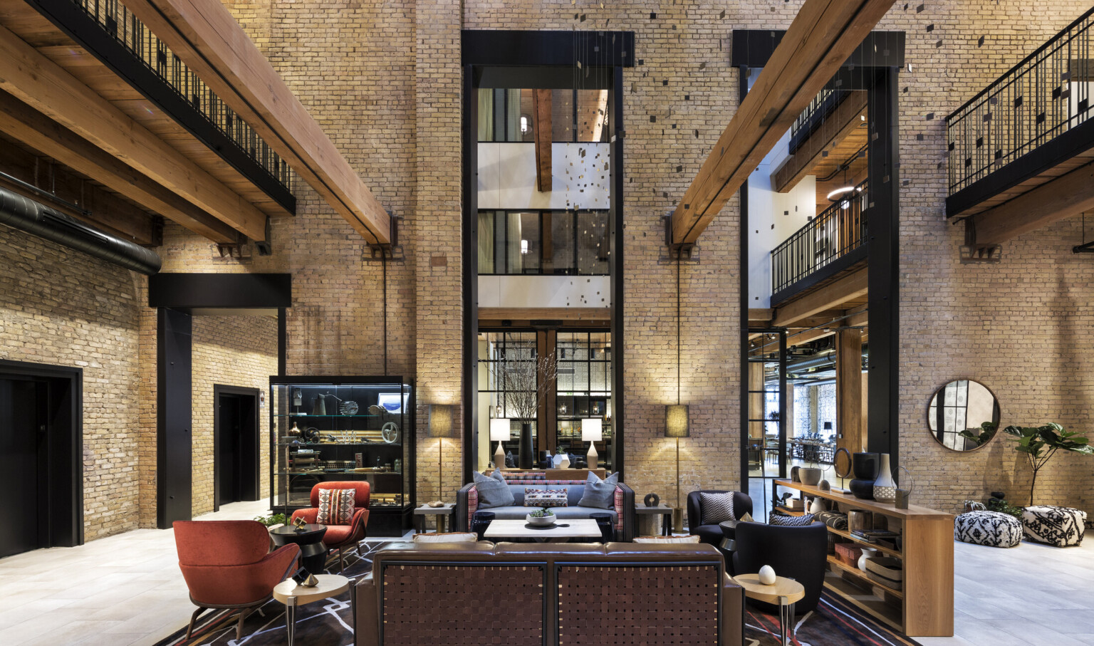 Interior atrium with exposed brick. Seating area at center and wood beams overhead. 2 walkways on sides above with metal rail, wood innovations grant, high performance design Interior atrium with exposed brick. Seating area at center and wood beams overhead. 2 walkways on sides above with metal rail, wood innovations grant, high performance design