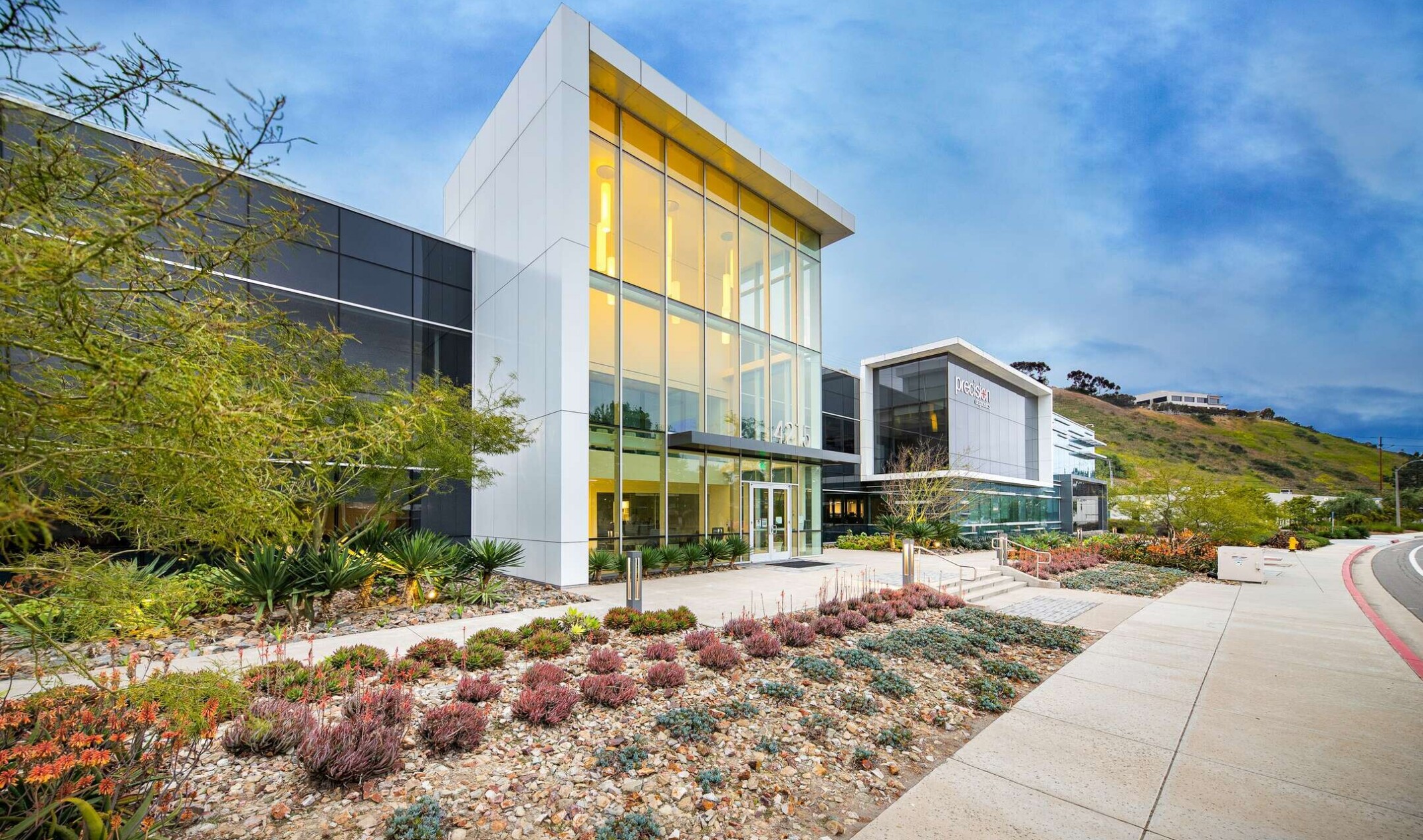 exterior of a modern building with a multi-facade treatment; entrance with floor to ceiling windows