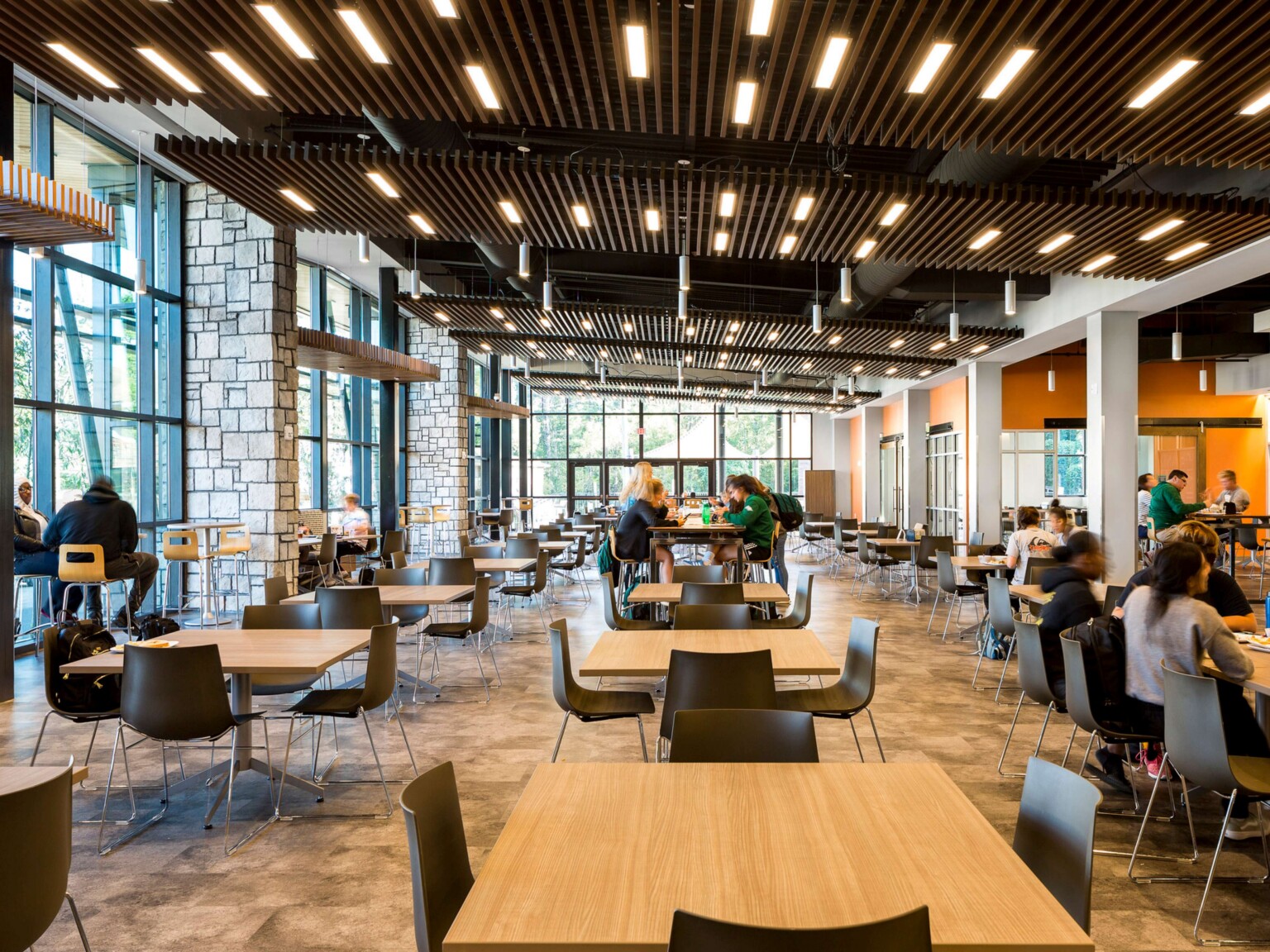 major collaboration space with low-top and high-top tables in a brightly, naturally lit building