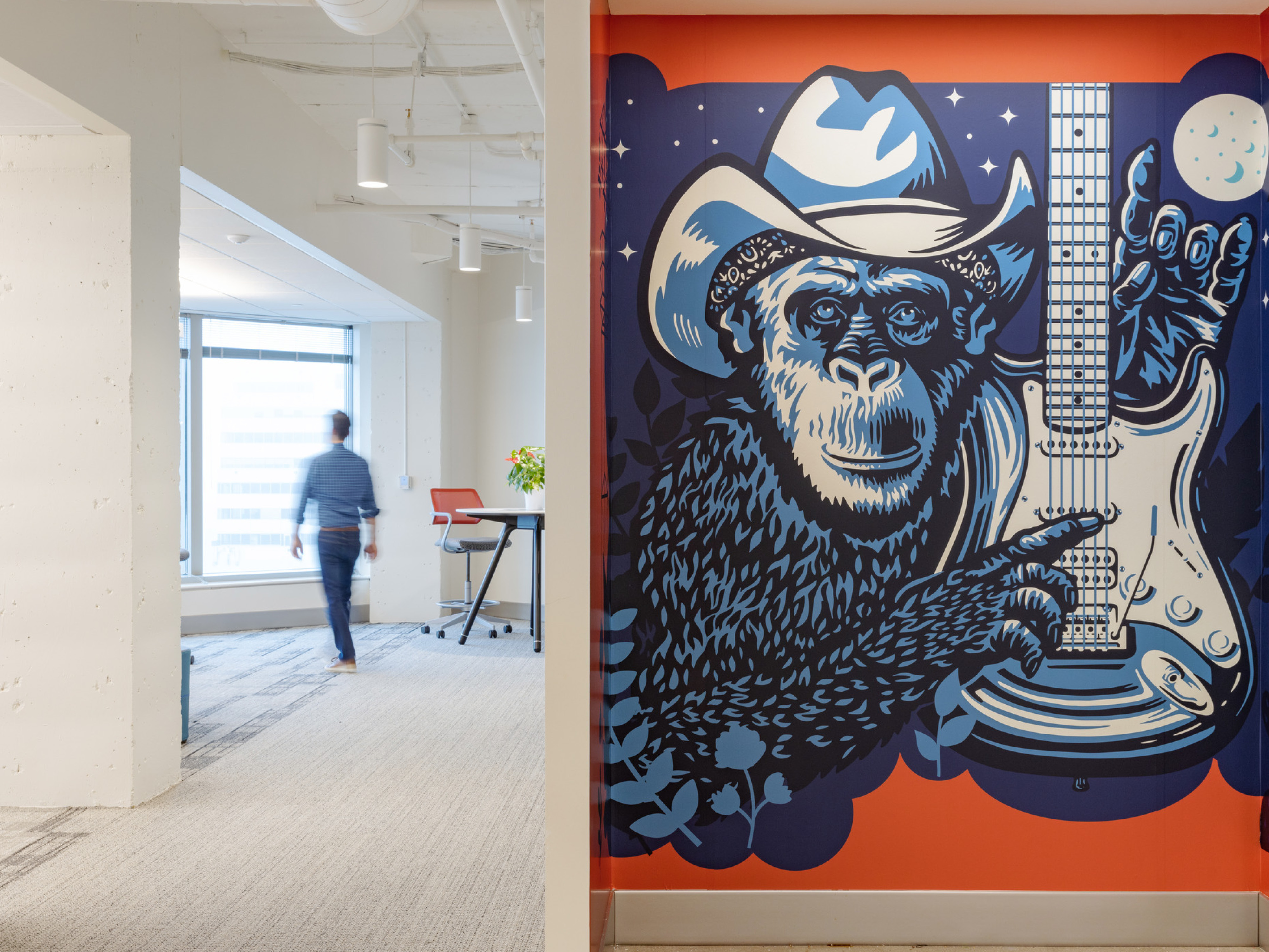 modern office hallway with mural of a guitar-playing monkey; DLR Group Austin office