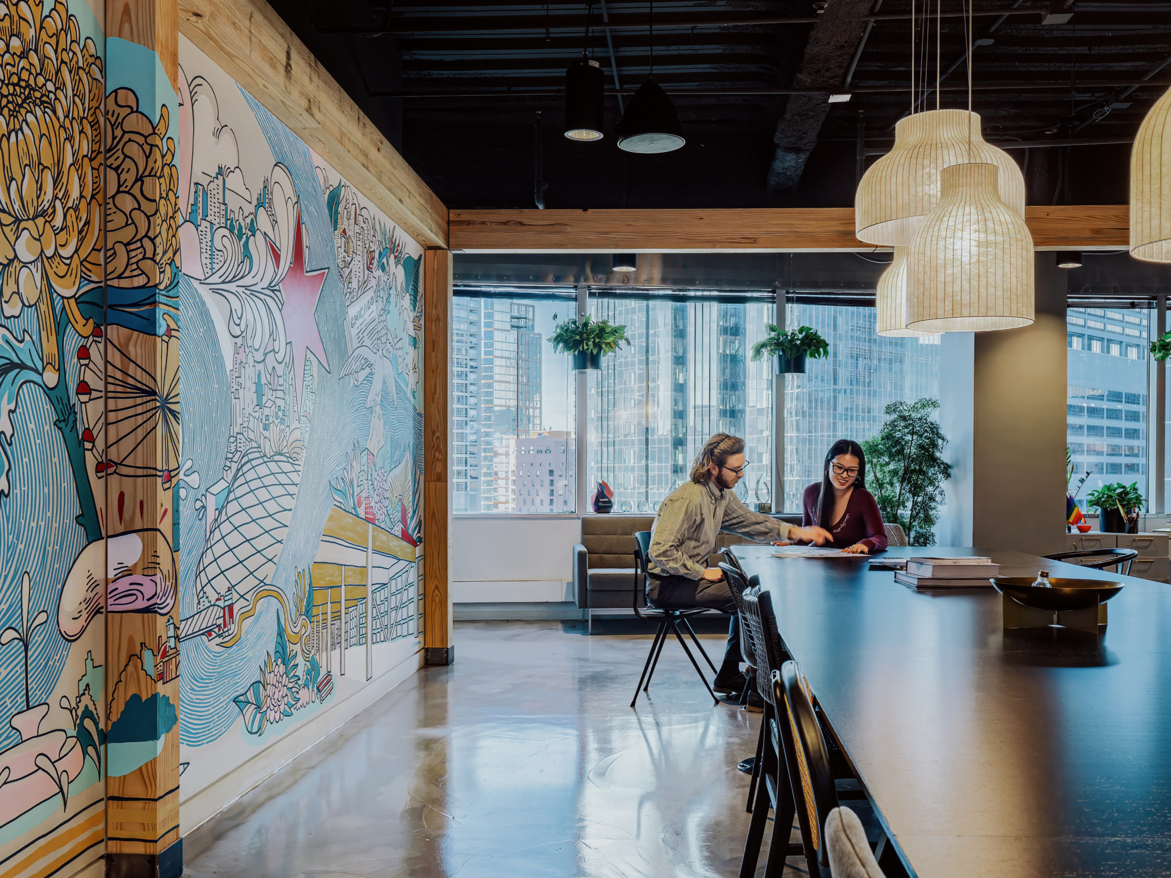 modern office large collaboration table with left hand mural wall and background windows with buildingscape; DLR Group Chicago office