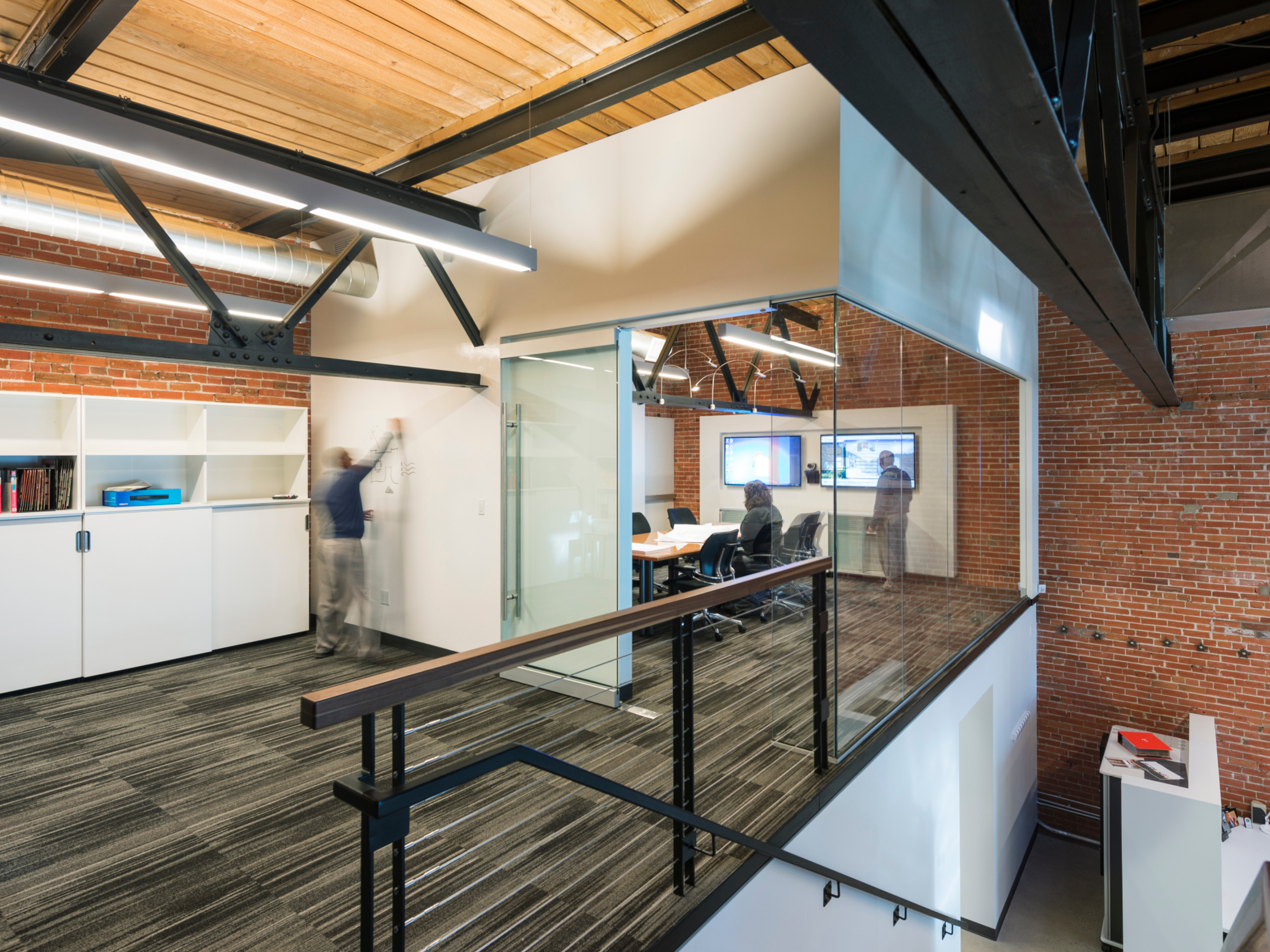 modern office space featuring a double height collaboration and desk space; people collaborating in rooms; DLR Group Colorado Springs office