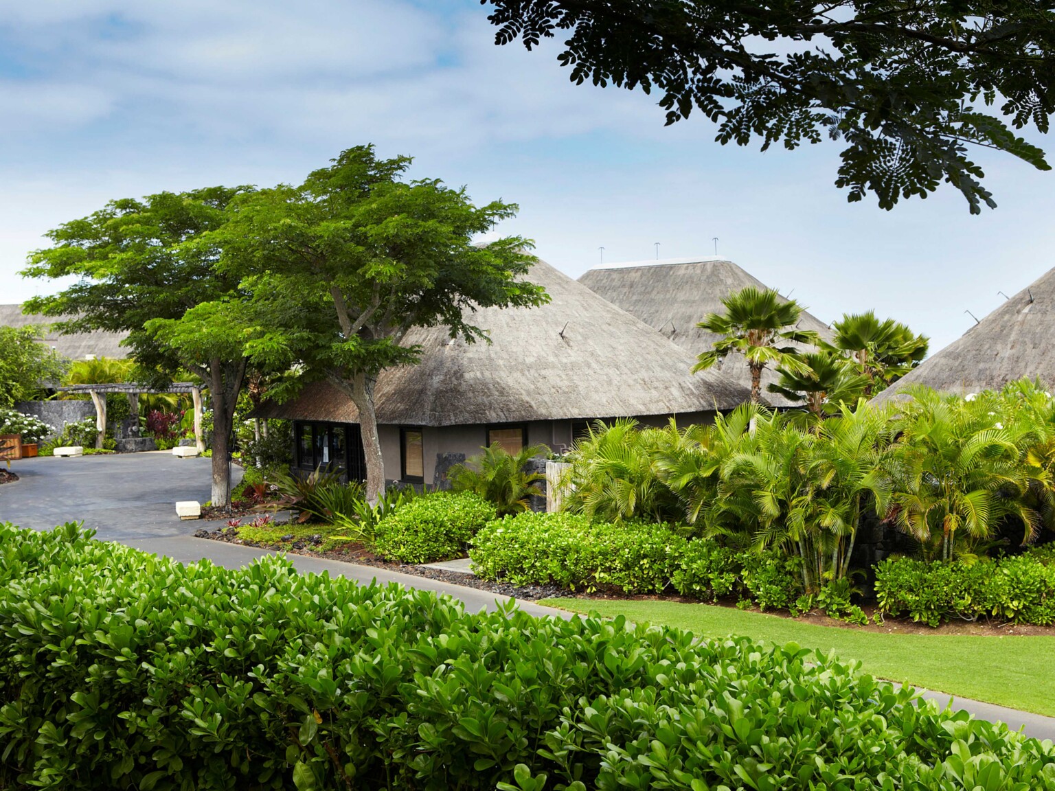 hawaiian resort villa with rustic roofing surrounded by lush greenery