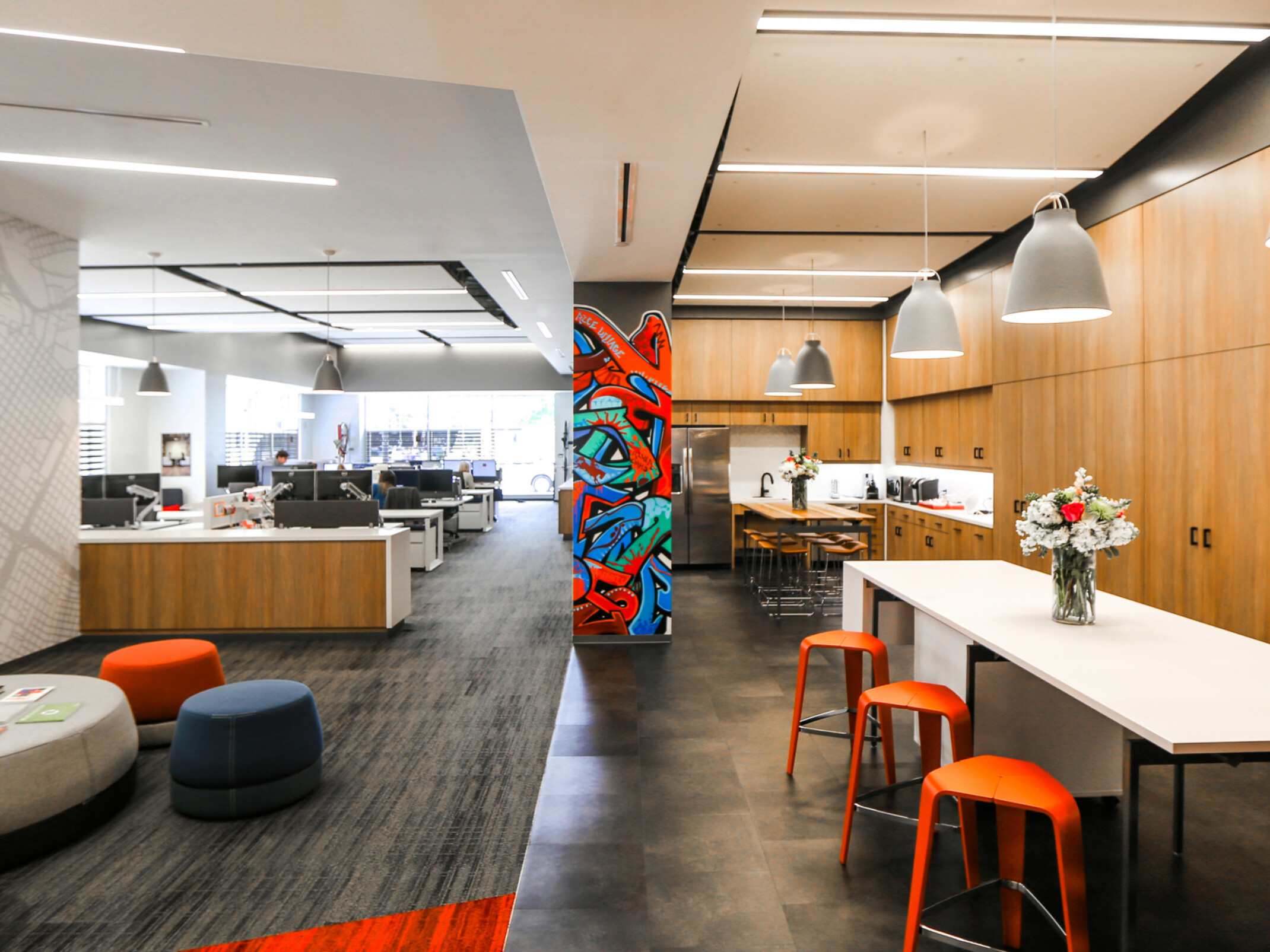Modern office entrance with communal kitchen and desk space in background; DLR Group Houston office