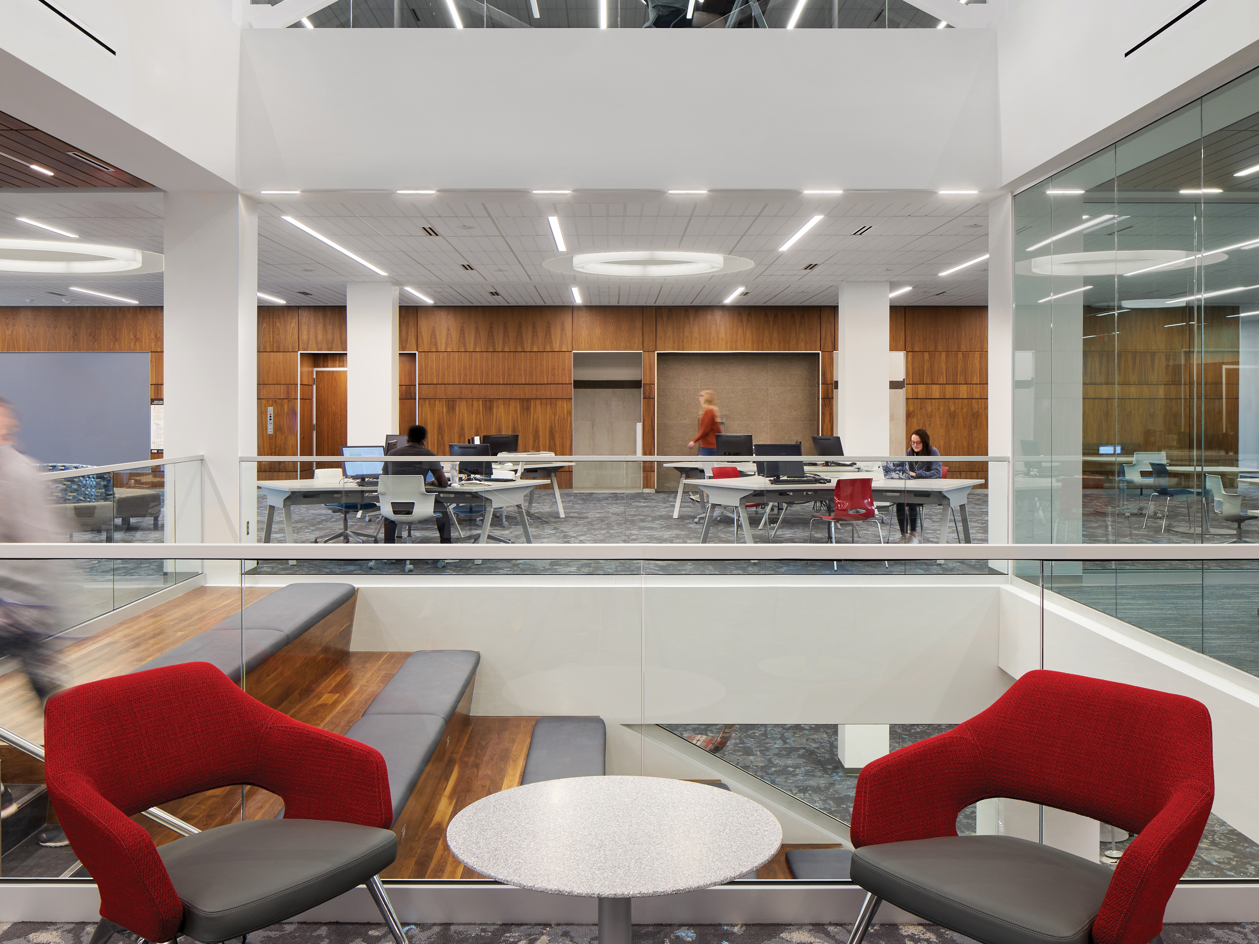 modern bright library space with central descending staircase; people at tables working