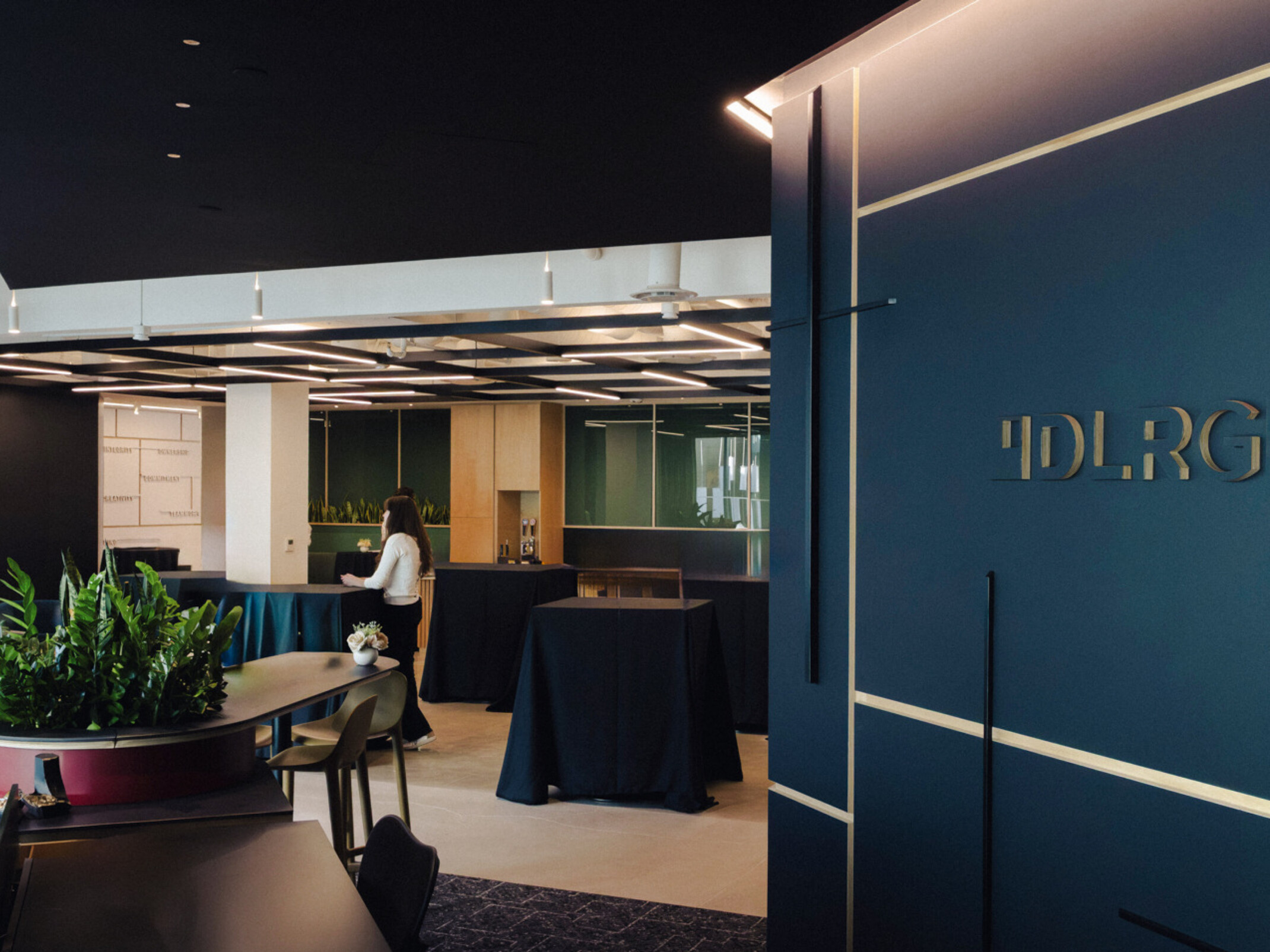 Modern office front entrance with a dark blue wall "DLR Group" opening to modular seating area; DLR Group San Diego office