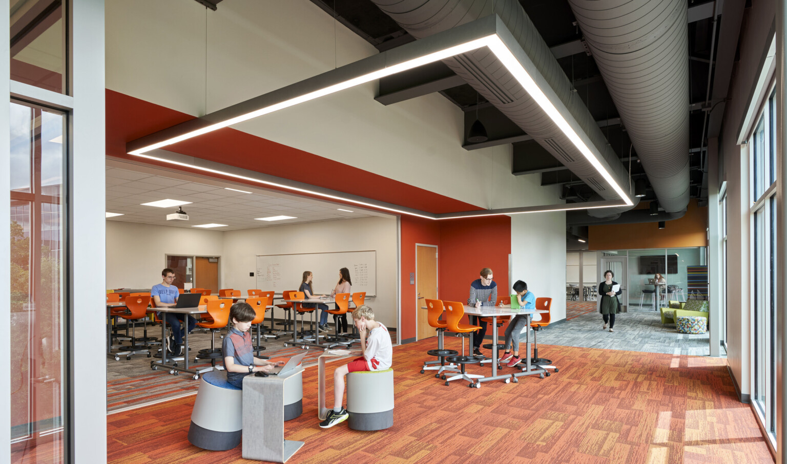 Large windows on right wall of orange and red seating area. 2nd room recessed off red accented wall. Rectangular light hangs