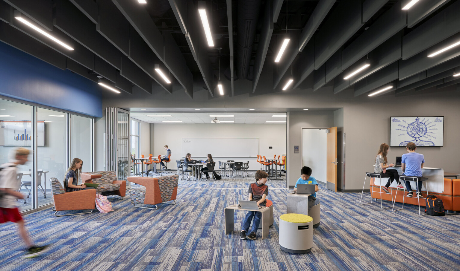 2 rooms with large windows, flexible wall in between. Blue patterned carpet under black ceiling with hanging slats and lights