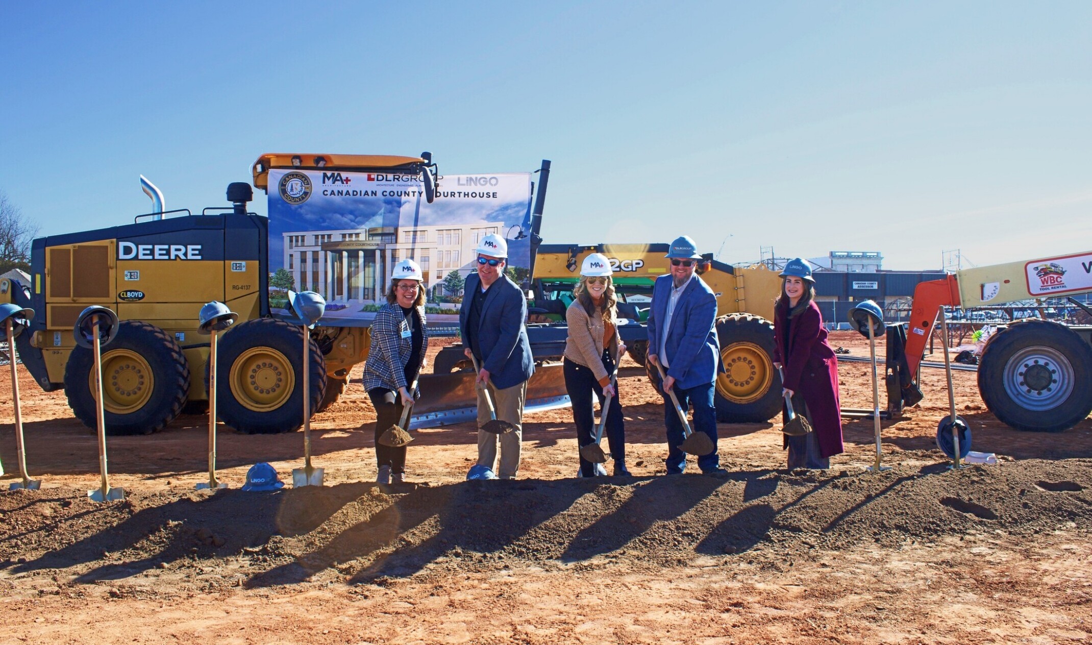 5 people standing in front of a construction site with a ceremonial pile of dirt to represent groundbreaking at Canadian County Courthouse