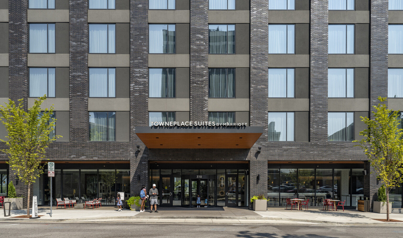 Front entrrance of the Towneplace Suites Nashville Downtown building with large windows above a red awning for cars to drop passengers off