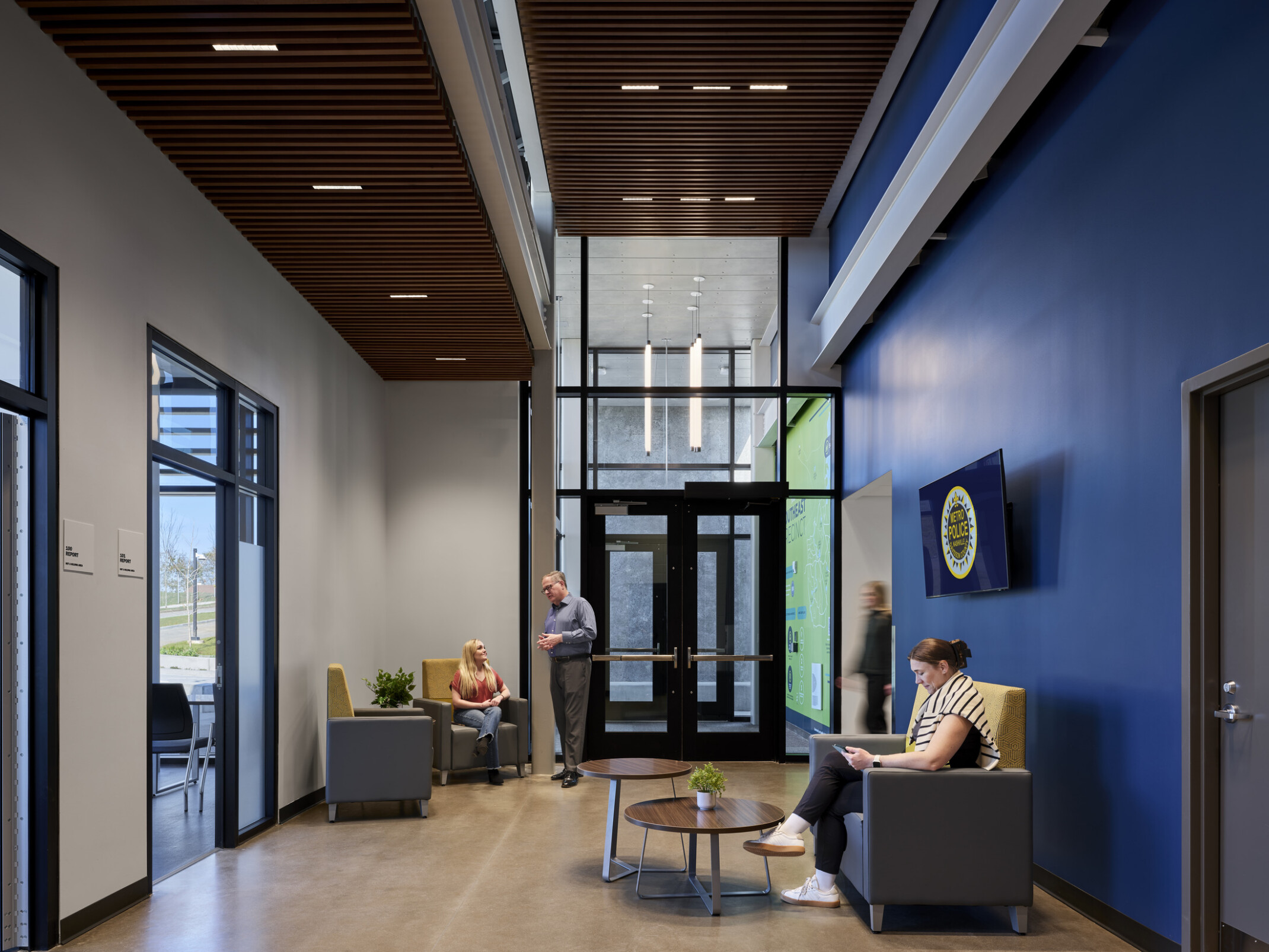 interior lobby hallway of a police precinct; seating area, blue wall, and interview rooms
