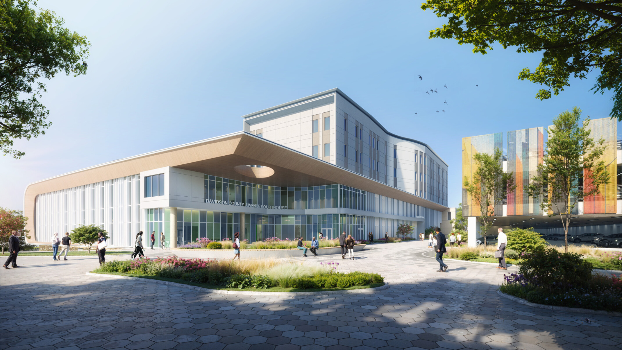 Exterior rendering of the Davidson County Juvenile Courthouse located on the Nashville Youth Center for Empowerment justice campus, with lush landscaping, people passing by, and a view of the new parking structure with multicolored mesh wall panels that enclose the second and third levels.