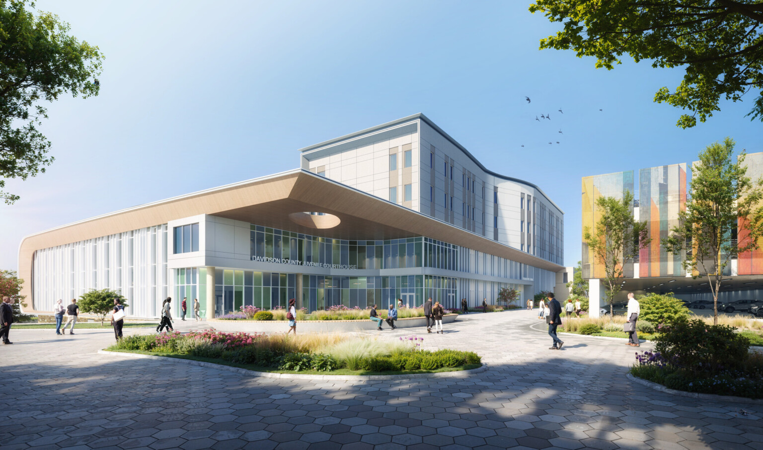 Exterior rendering of the Davidson County Juvenile Courthouse located on the Nashville Youth Center for Empowerment justice campus, with lush landscaping, people passing by, and a view of the new parking structure with multicolored mesh wall panels that enclose the second and third levels.